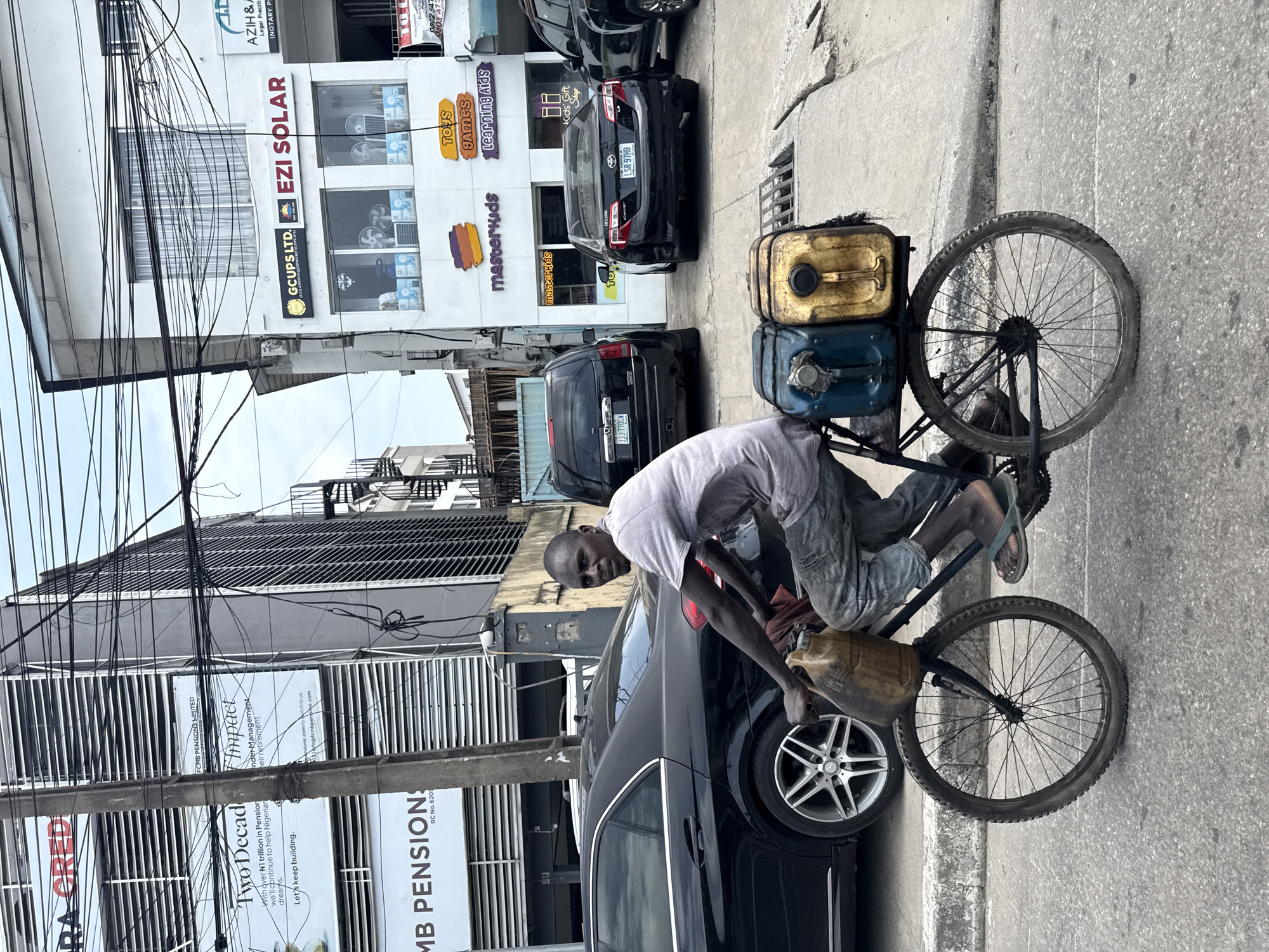 Delivery workers converse, cyclist transfers fuel in Lagos area