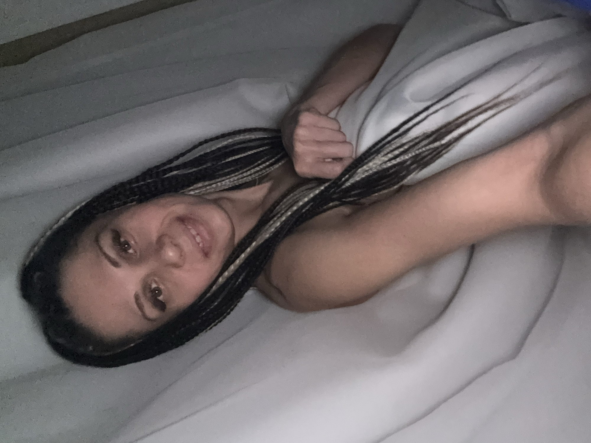 Woman with braided hair holds orange fruit while lying down