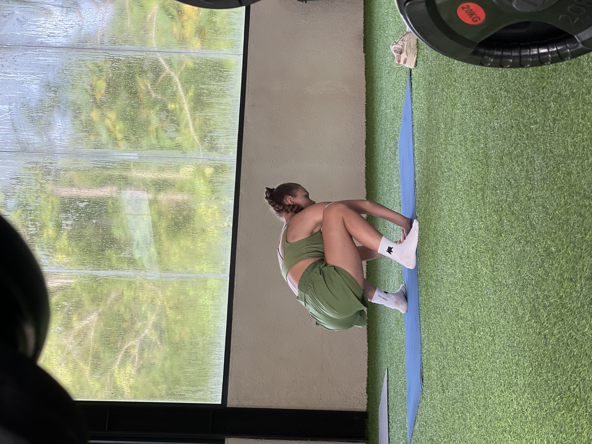 Woman in athletic wear sits on mat indoors