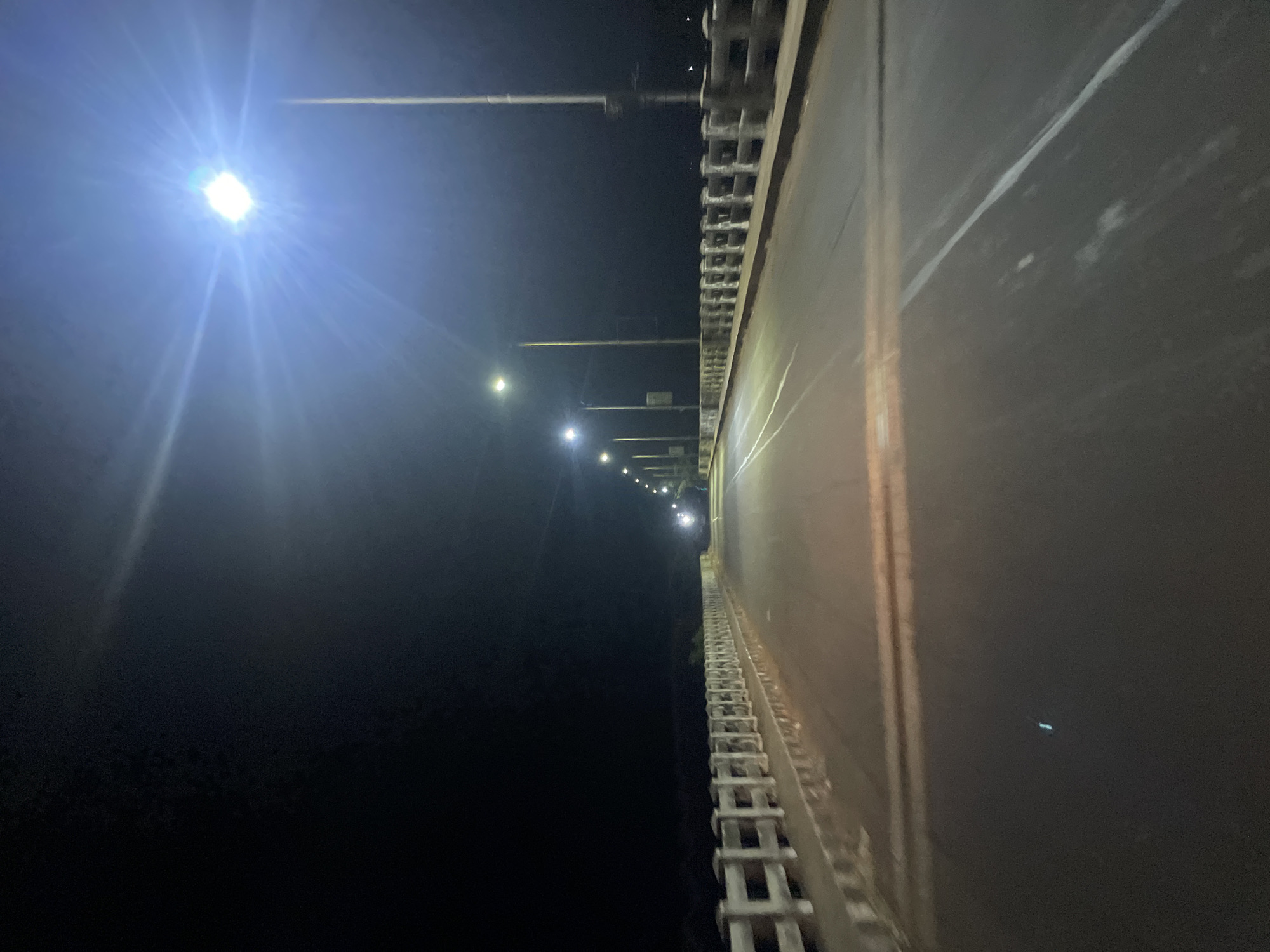 Nighttime streetlights illuminate dark roadway in Paliem, India