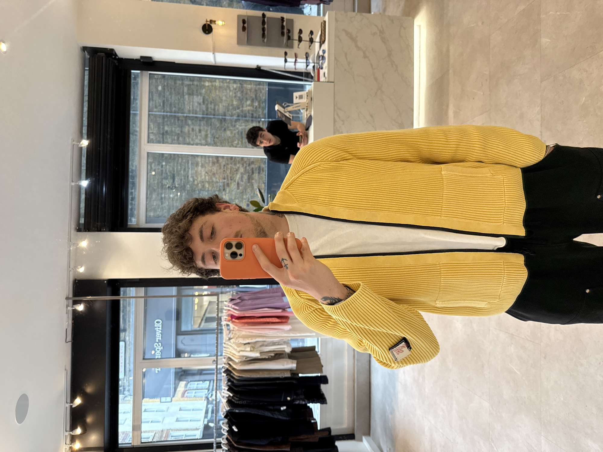 Young man takes mirror selfies in London clothing store