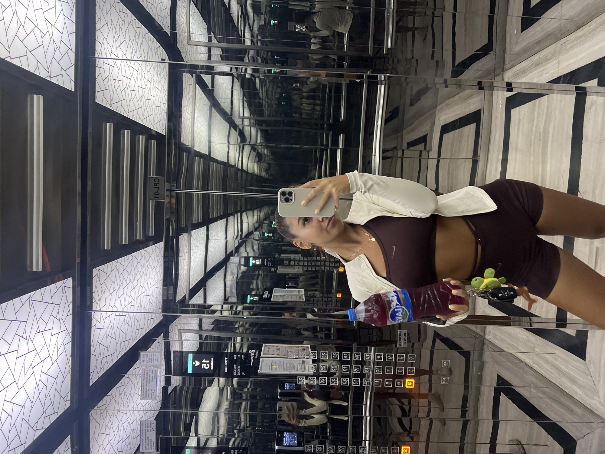 Woman captures mirrored selfie in reflective elevator