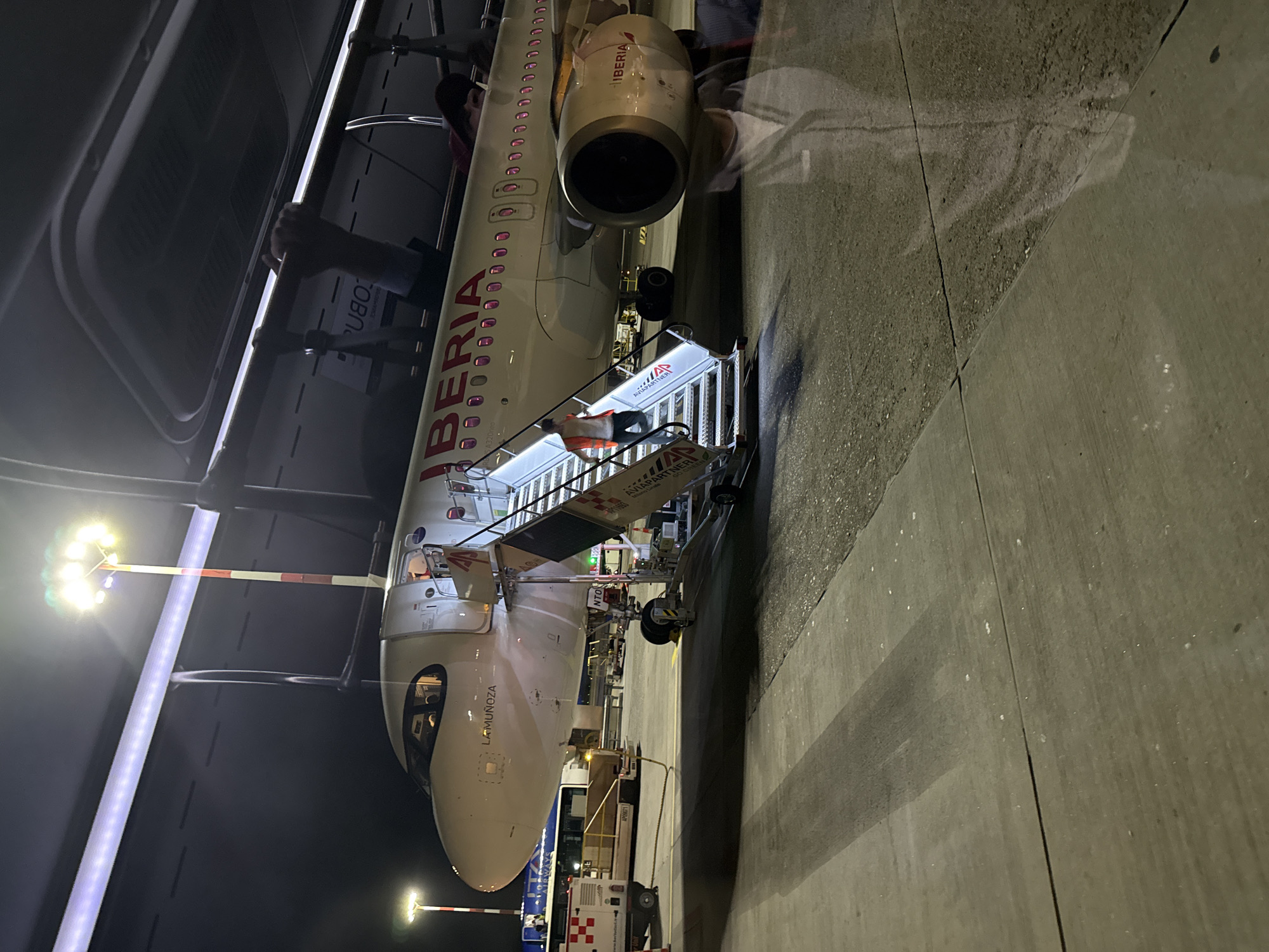 Iberia A320 parked at night on a Milan-area tarmac