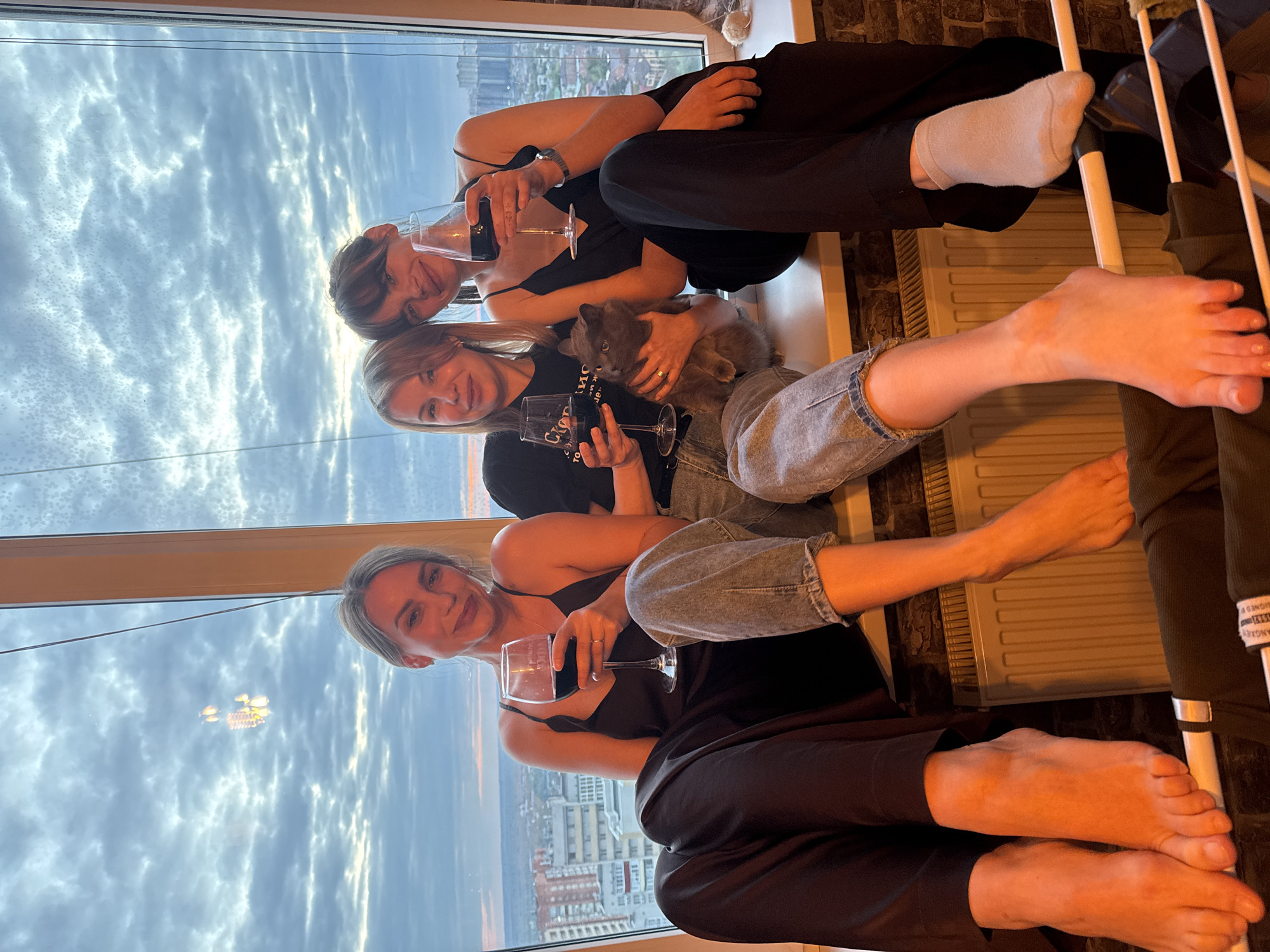 Three women share wine at sunset window in Rostov-on-Don