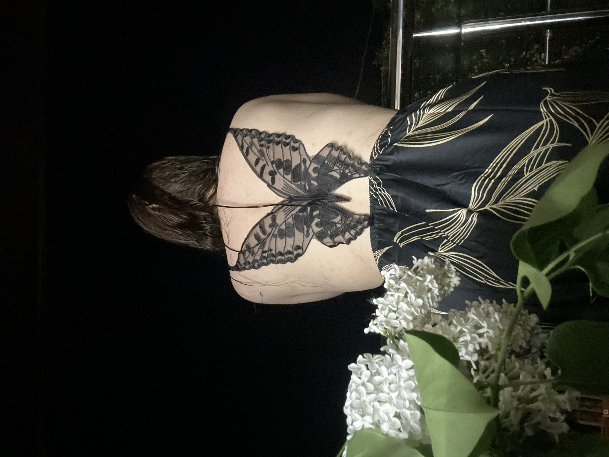 Person with butterfly tattoo observes blooming lilacs in Nizhny Novgorod
