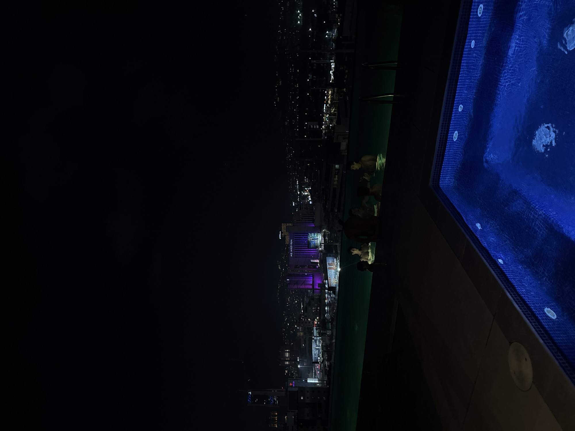 Rooftop pool overlooks San Pedro Garza García skyline at night