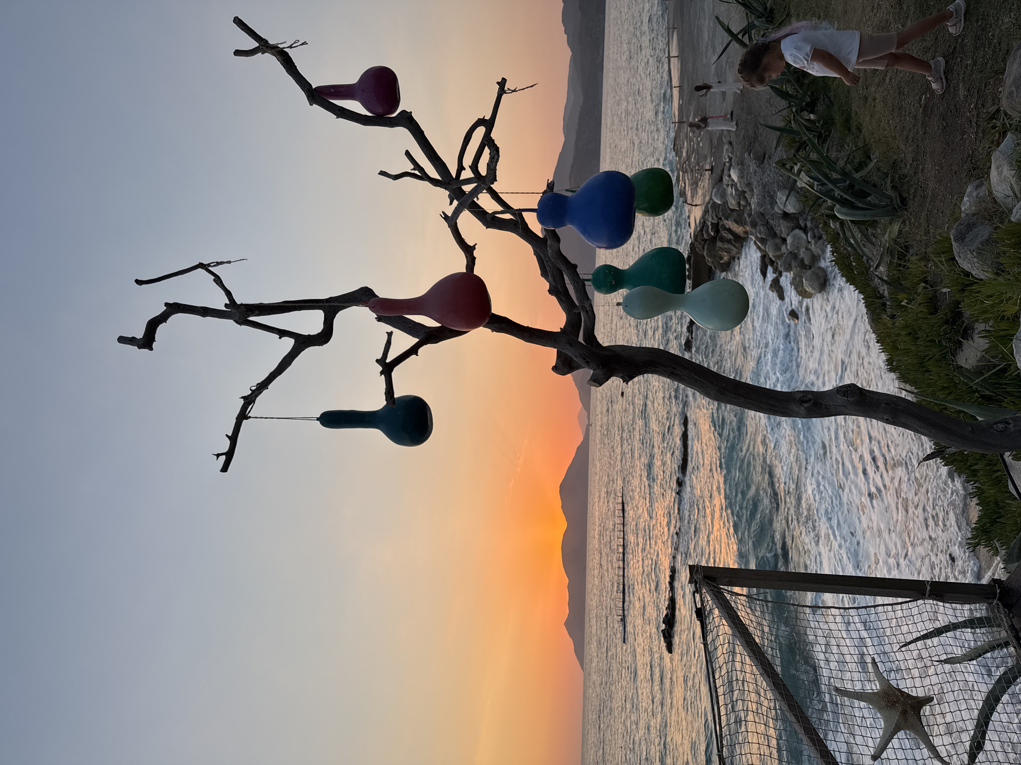 Ornament-hung bare tree frames a Fethiye sunset over the sea