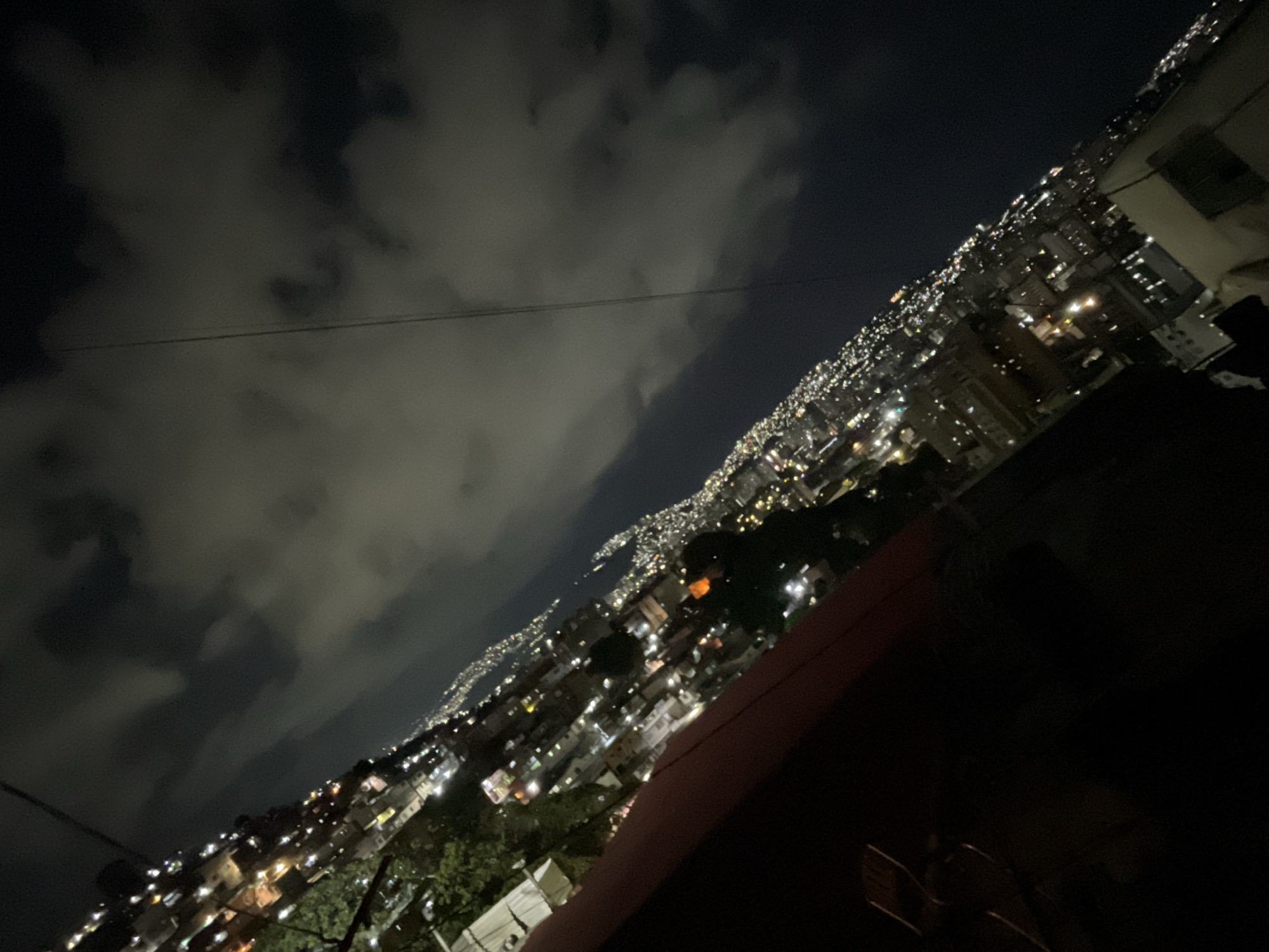 Caracas hillside neighborhoods illuminate cloudy night sky