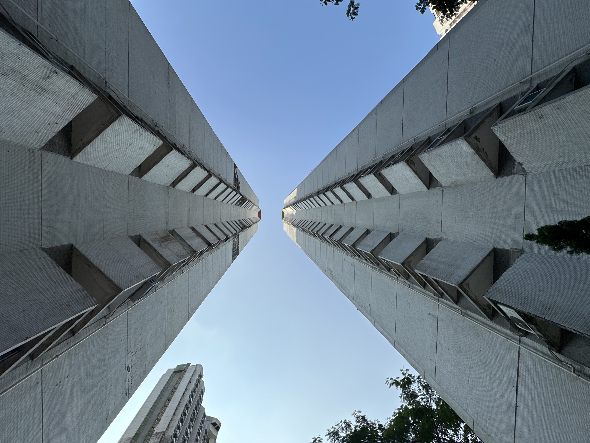 Looking up at two mosaic-tiled apartment towers in Hong Kong.
