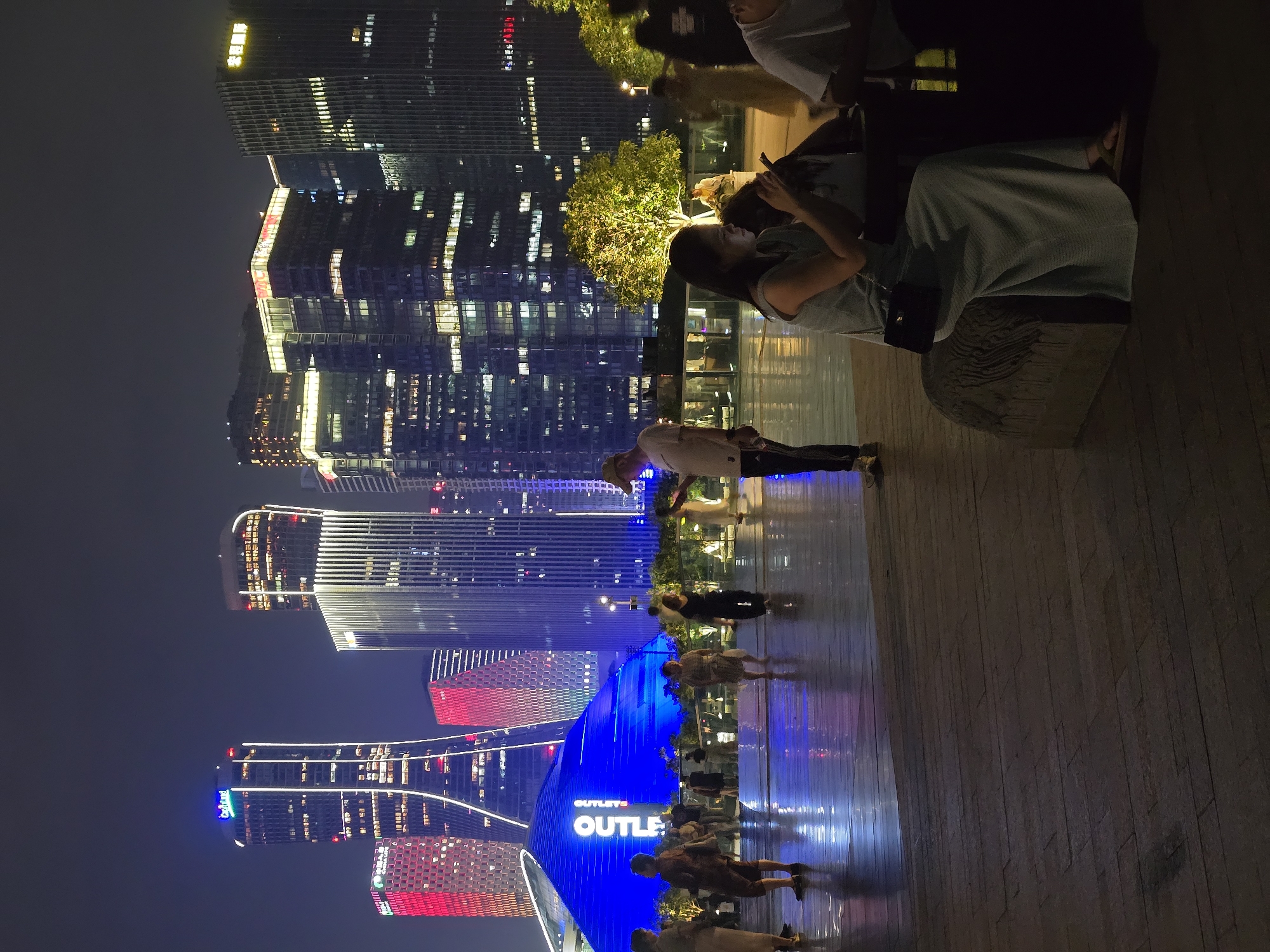 Evening strollers enjoy illuminated Hangzhou skyline and waterfront promenade