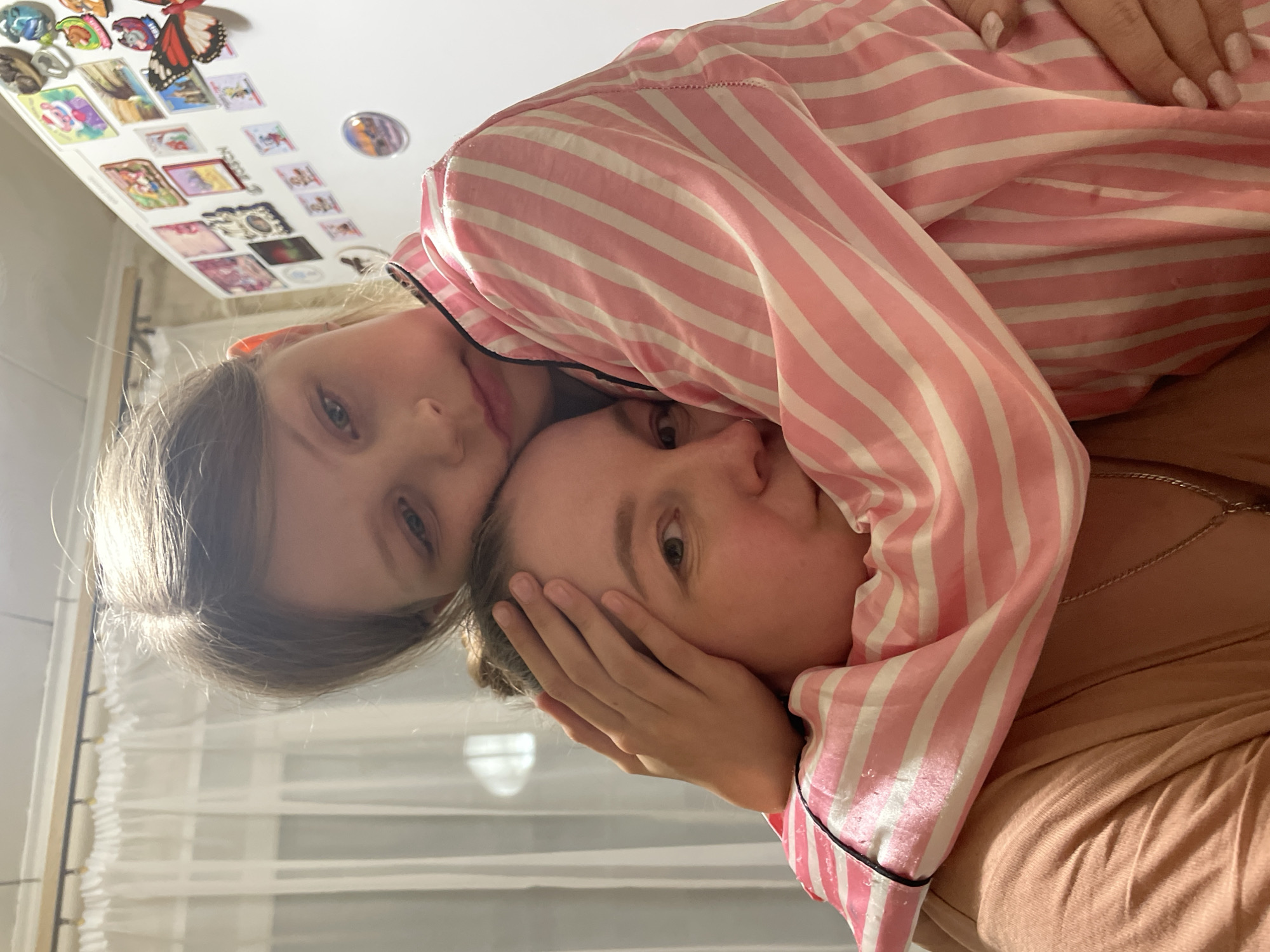 Child in striped pajamas rests on companion's shoulder in Izhevsk