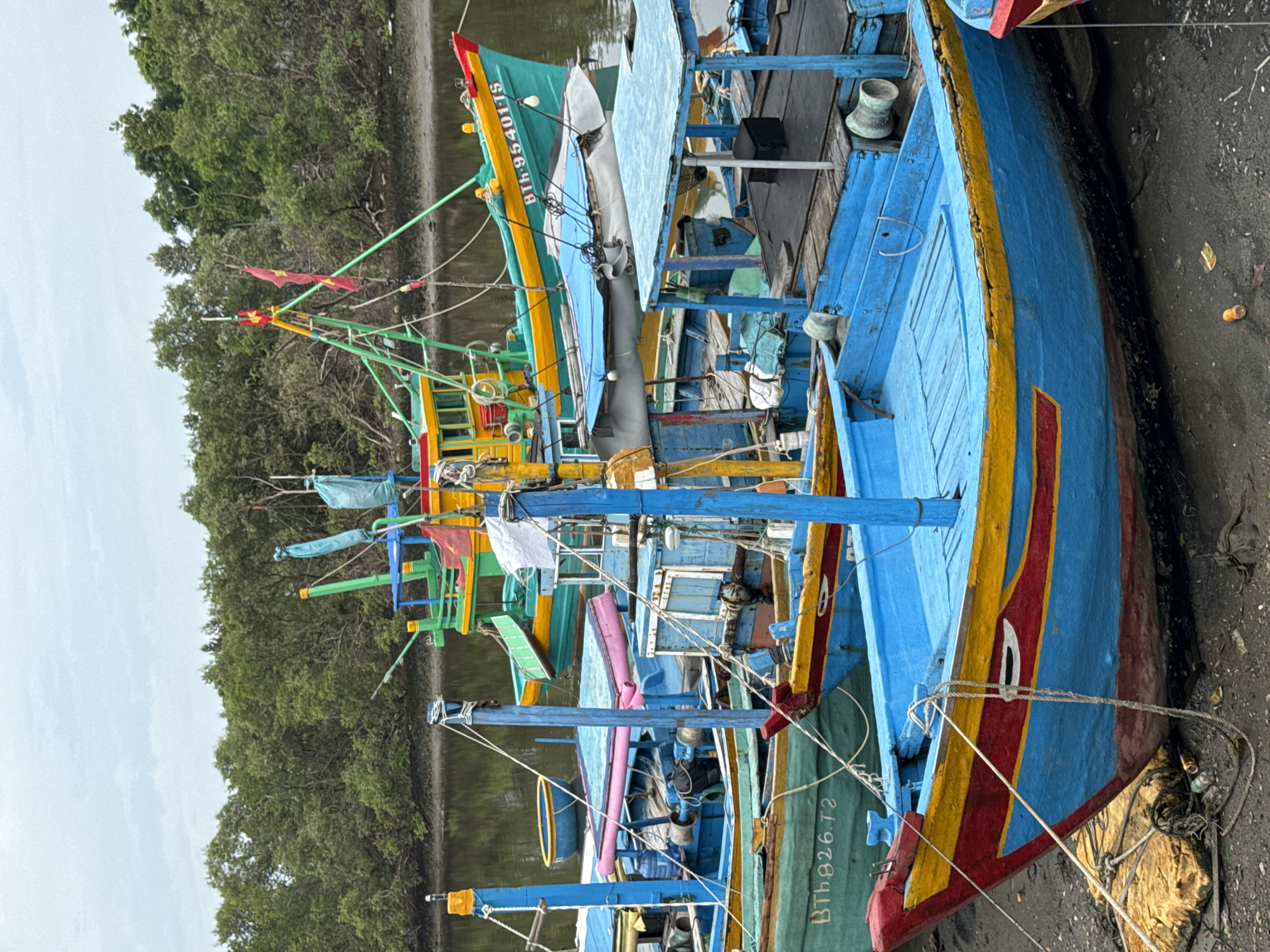 Fishing boats line the muddy shore in Phú Thủy, Vietnam