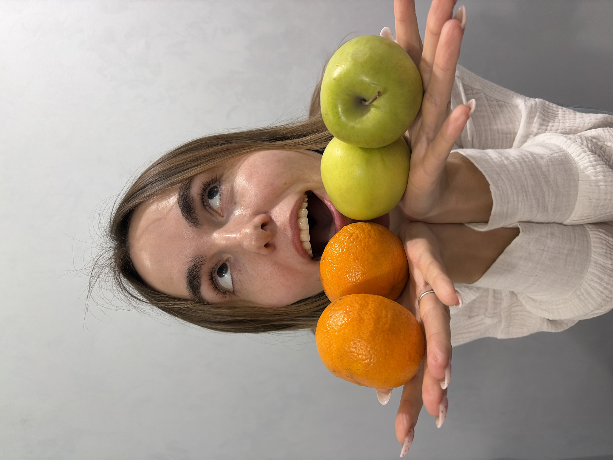 Person holds fruit to eyes in Neftekamsk kitchen