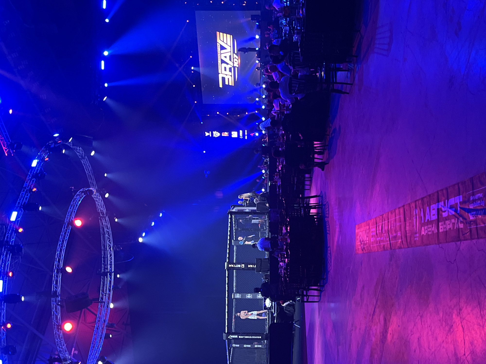 Indoor combat sports event under blue and pink dramatic lighting