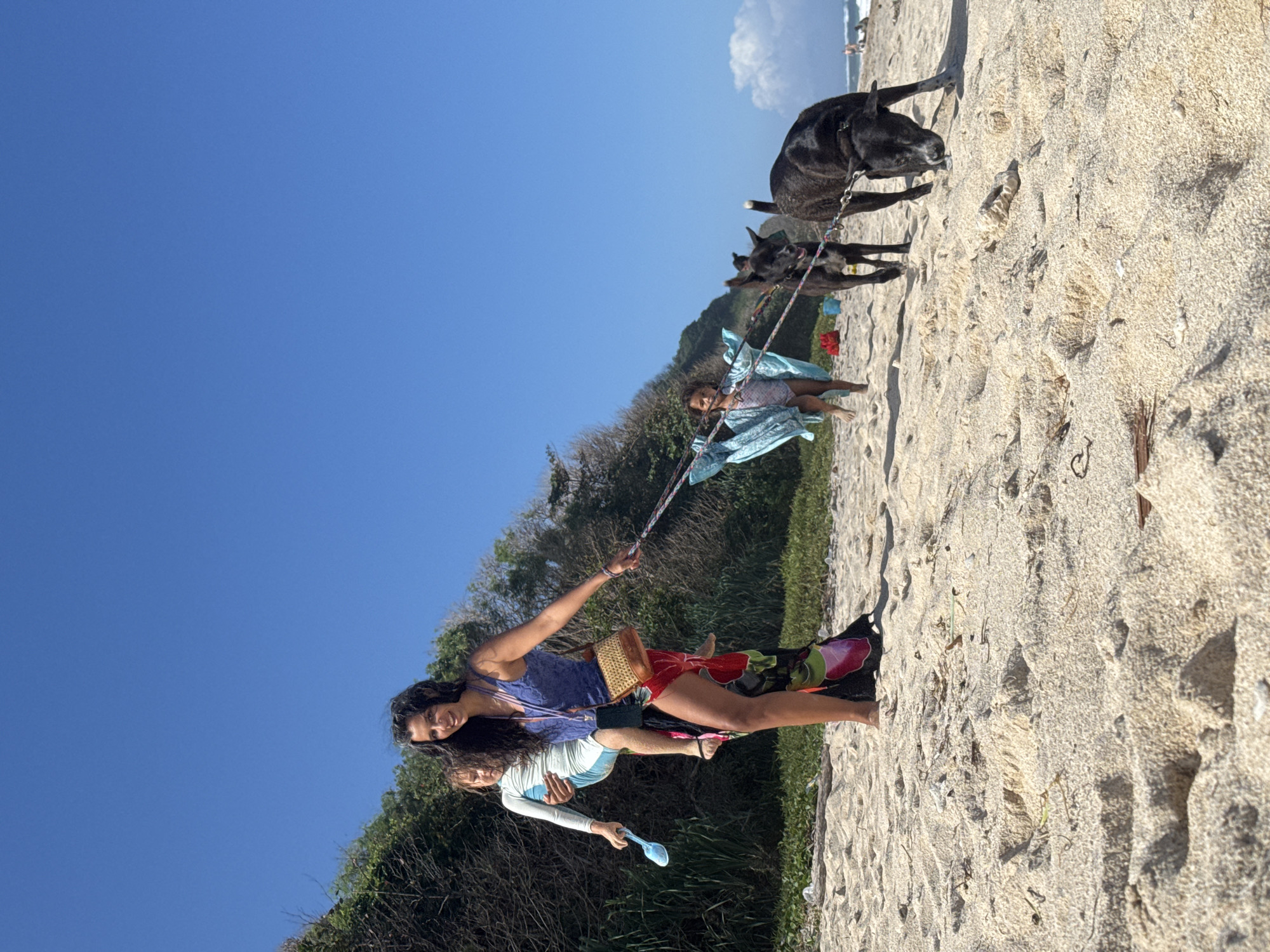 Paragliders, beachgoers, and excavators share a Bali morning shore
