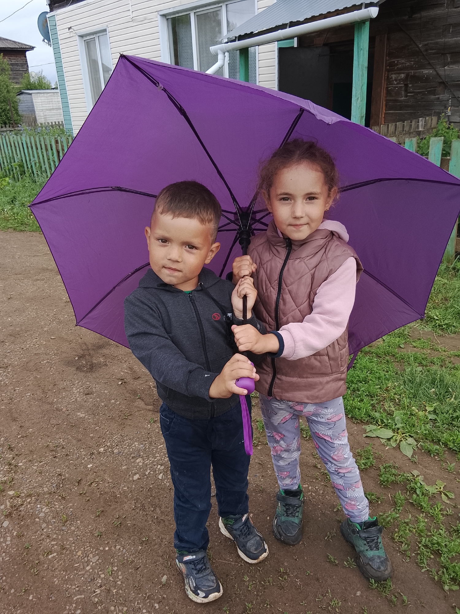 Children play with purple umbrella in rural Russian town