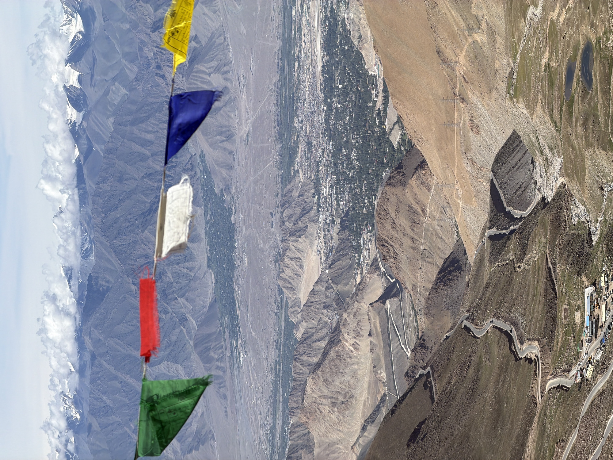 Royal Enfield parked above Leh, prayer flags and mountain views
