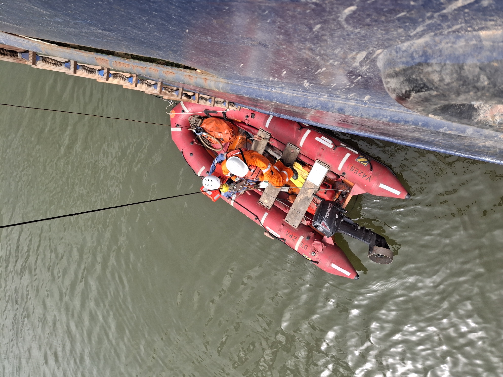 Maritime workers conduct boat operations near cargo ship