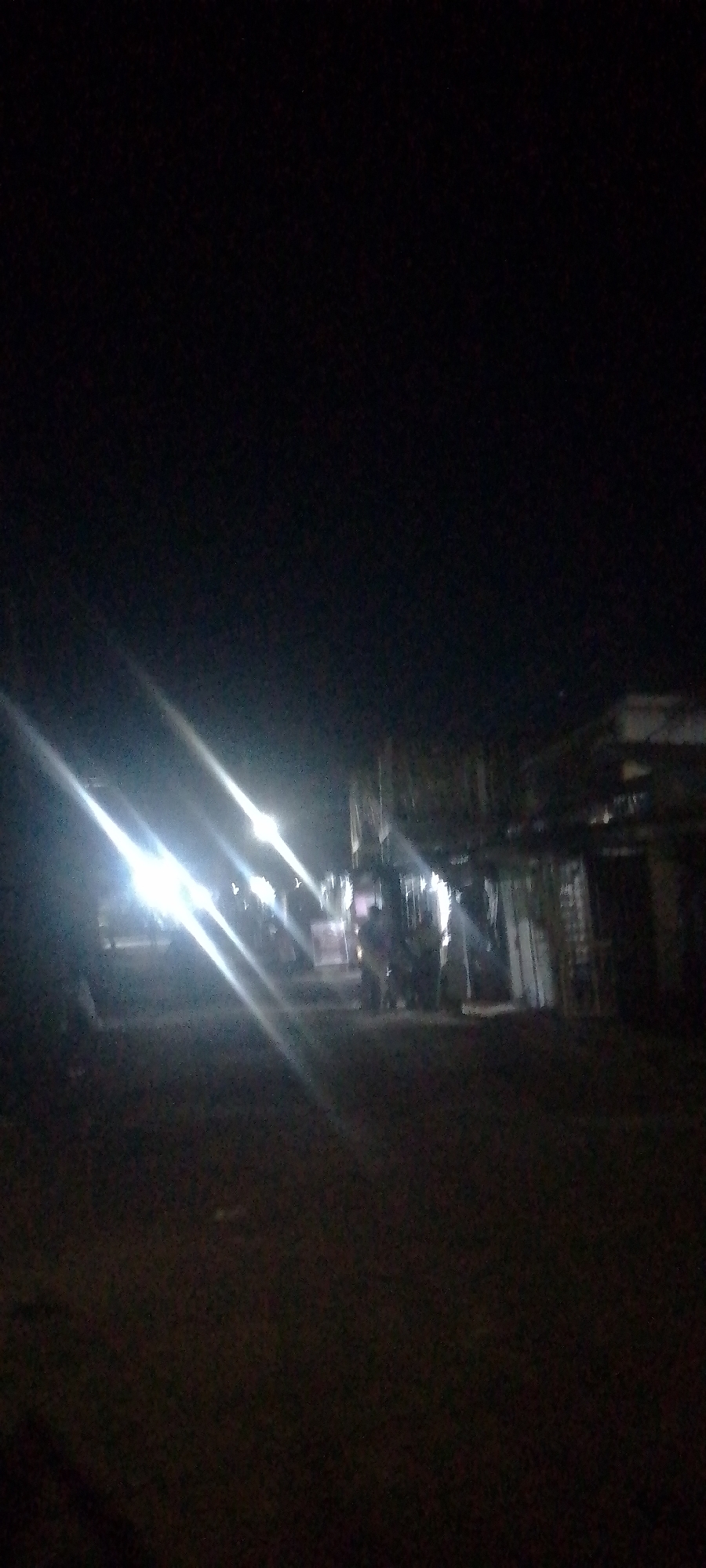 Bright lights illuminate dark street scene at night