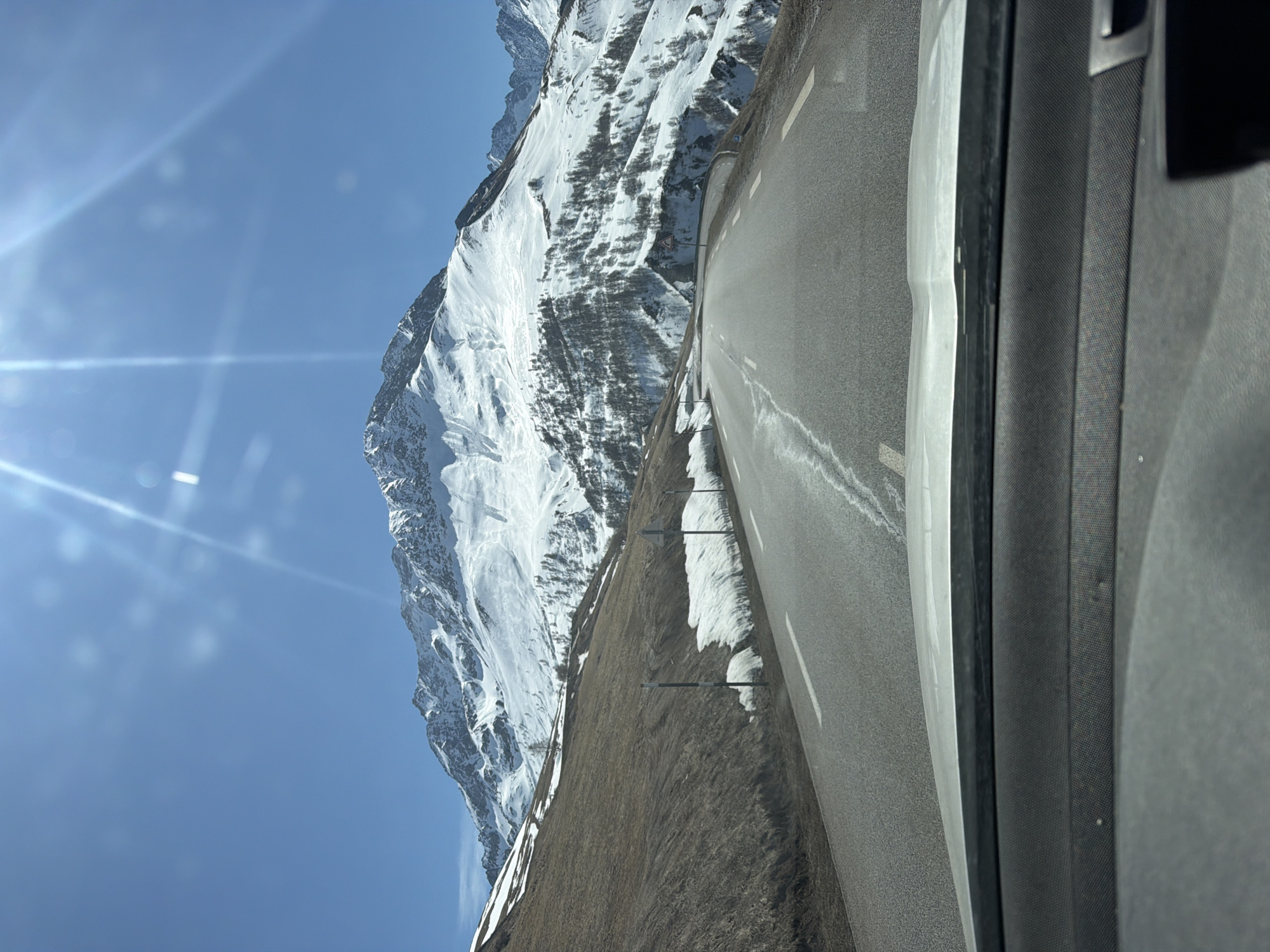 Vehicle travels mountain road with alpine views in France