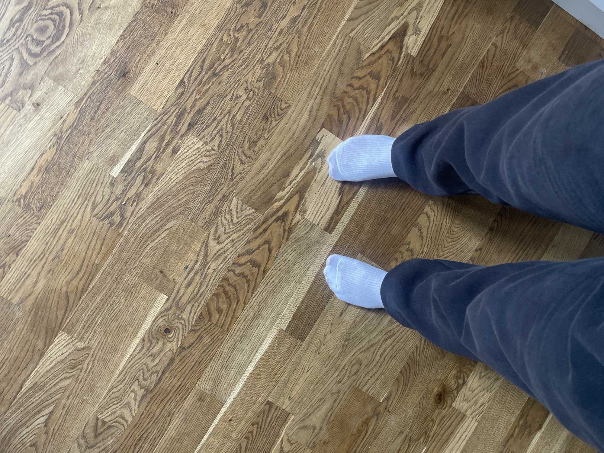Person in sweatpants and white socks on wooden floor