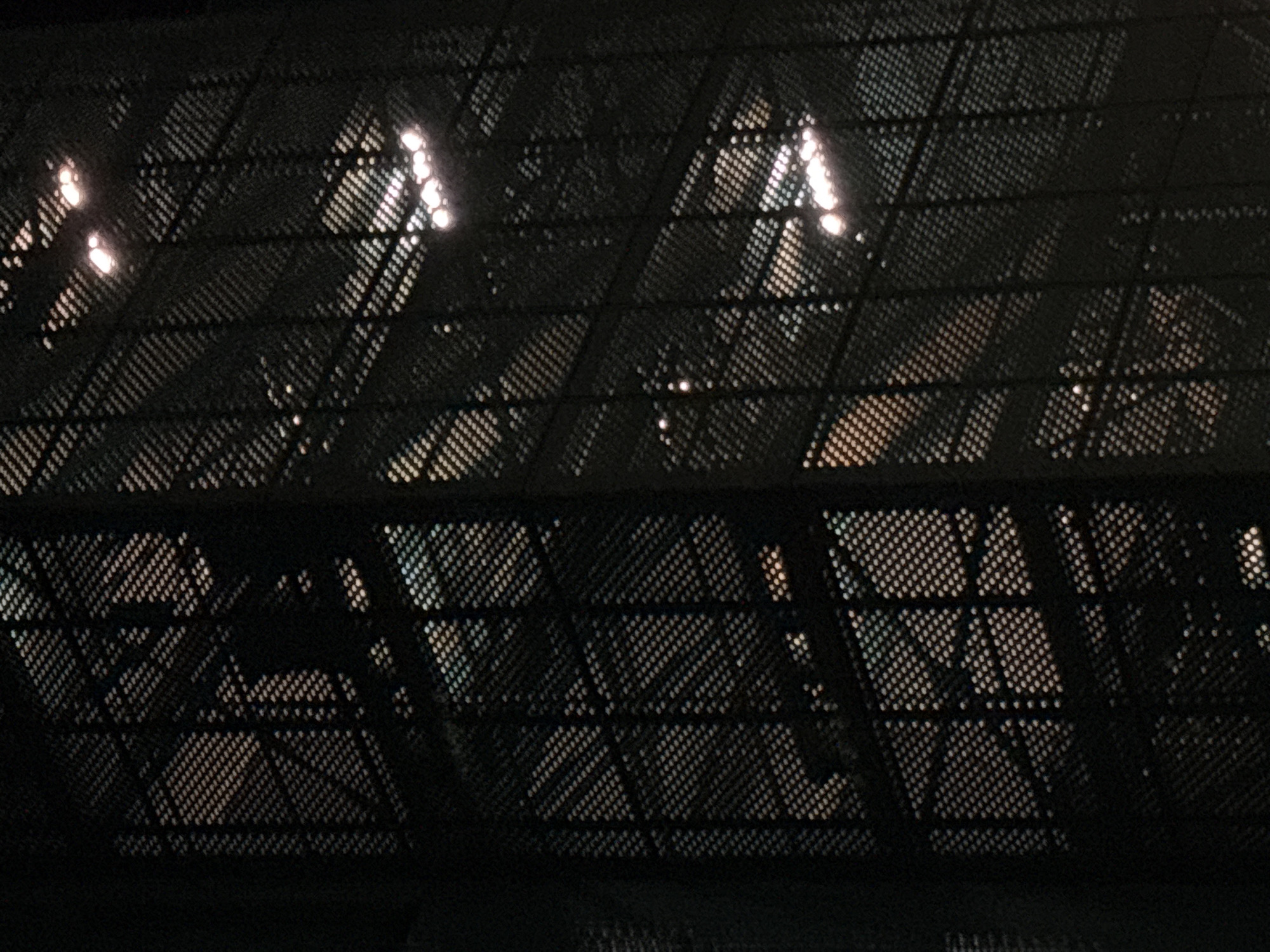 Nighttime textures on a Bishkek street — metal, shadow, foliage