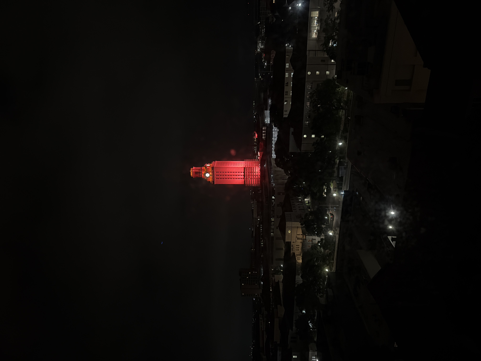 UT Tower glows red in Austin nighttime cityscape