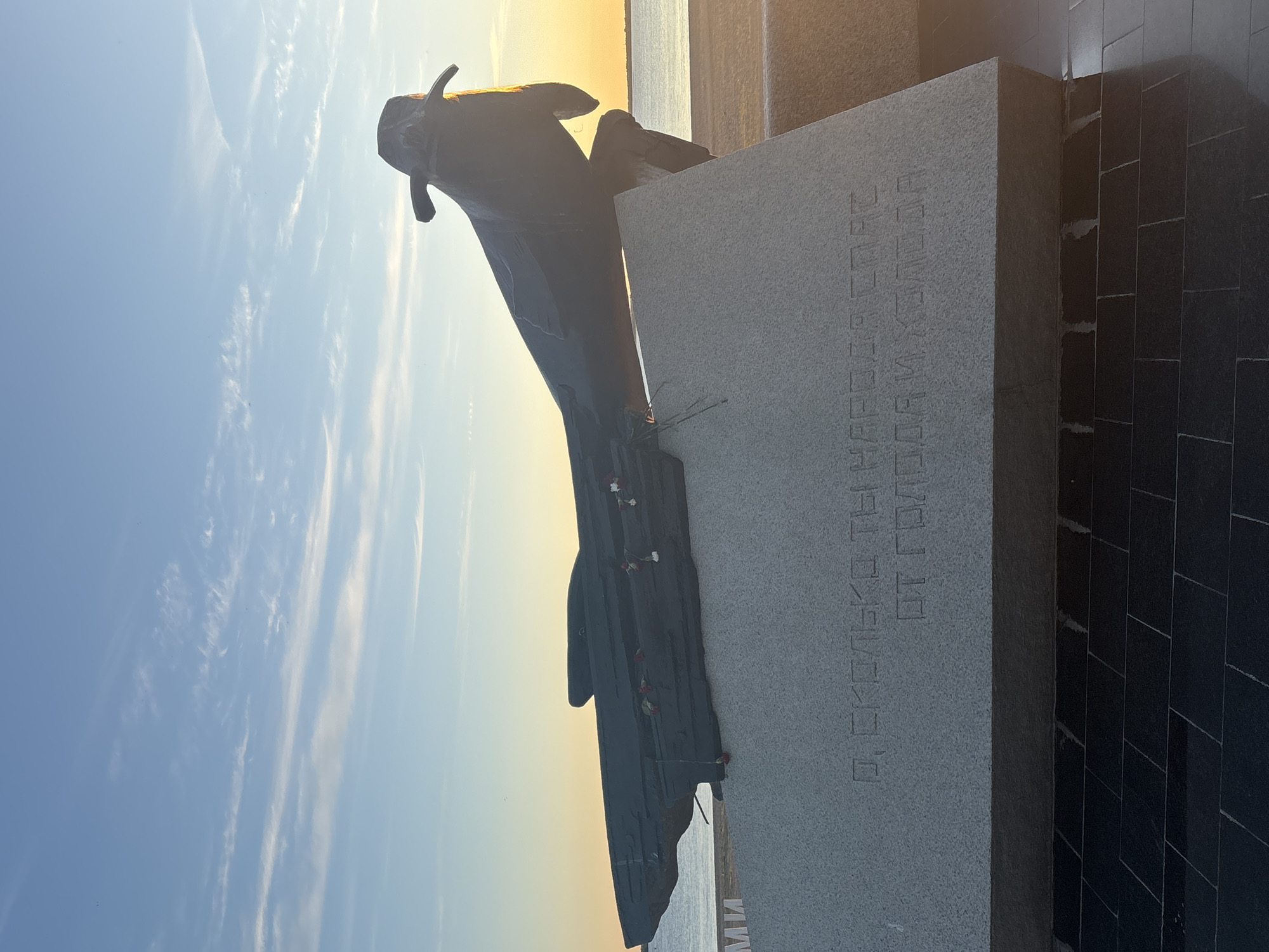 Arkhangelsk waterfront at golden hour: sculptures, coast, and sky