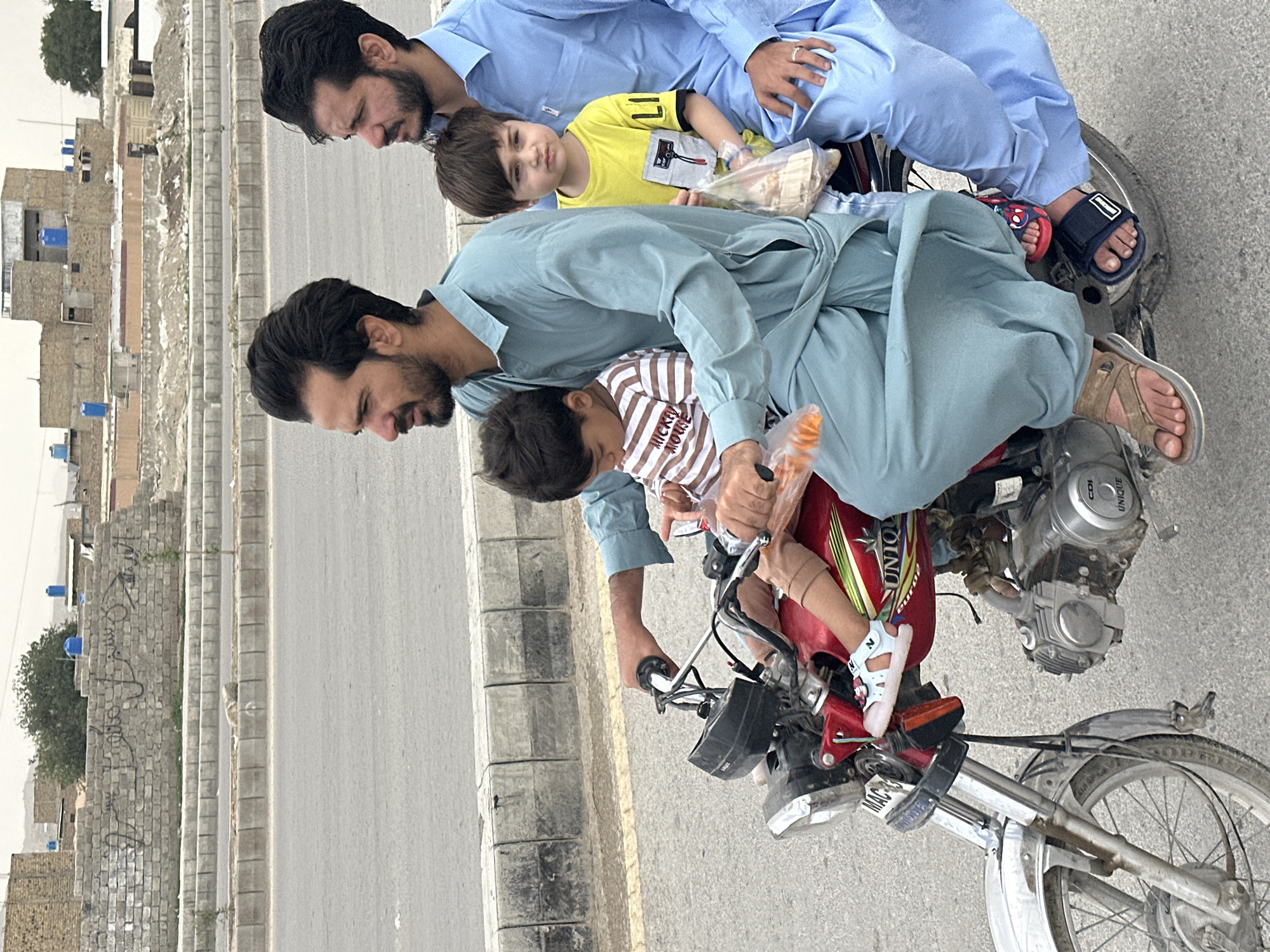 Family of three spotted sharing motorcycle ride in Quetta