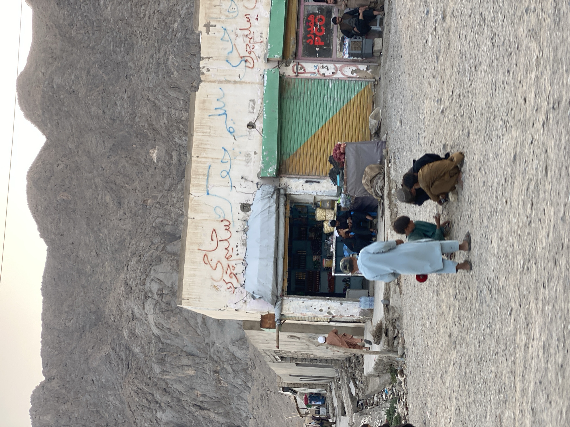 Unpaved street scene amid Kandahar's rugged mountain backdrop