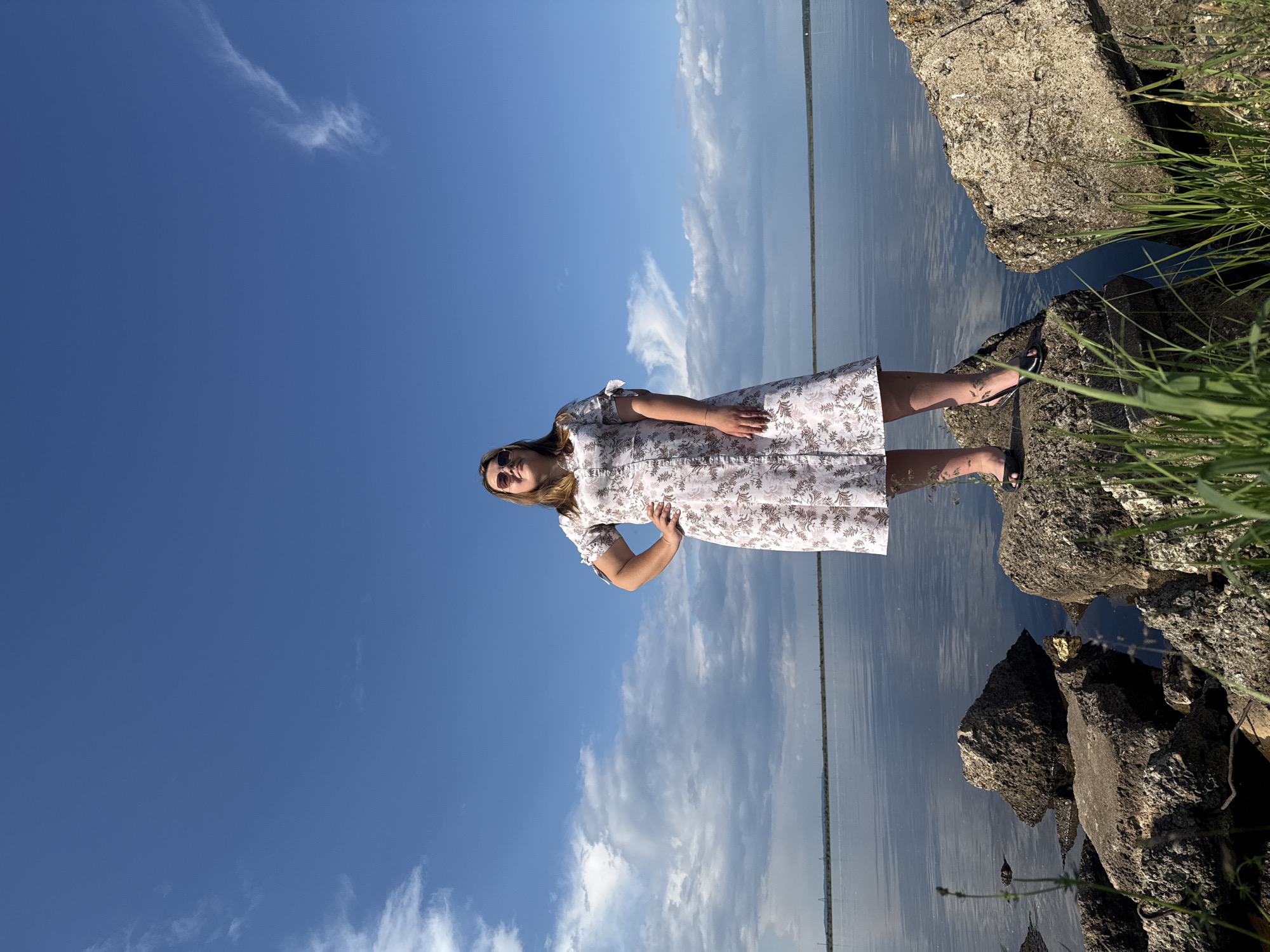 Woman poses by water under dramatic sky in Chaikovsky