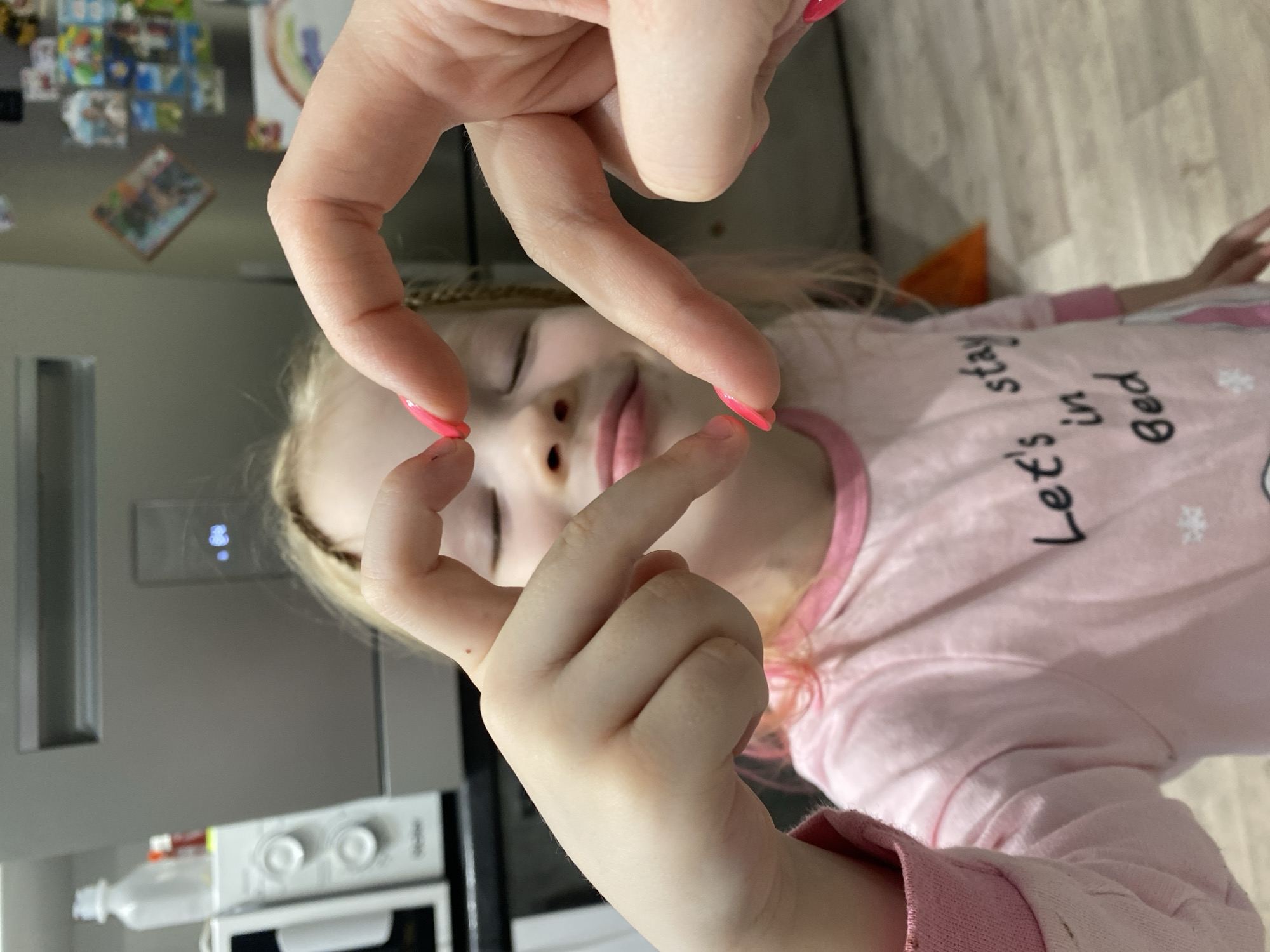 Child in pink pajamas photographed with heart gesture in Izhevsk