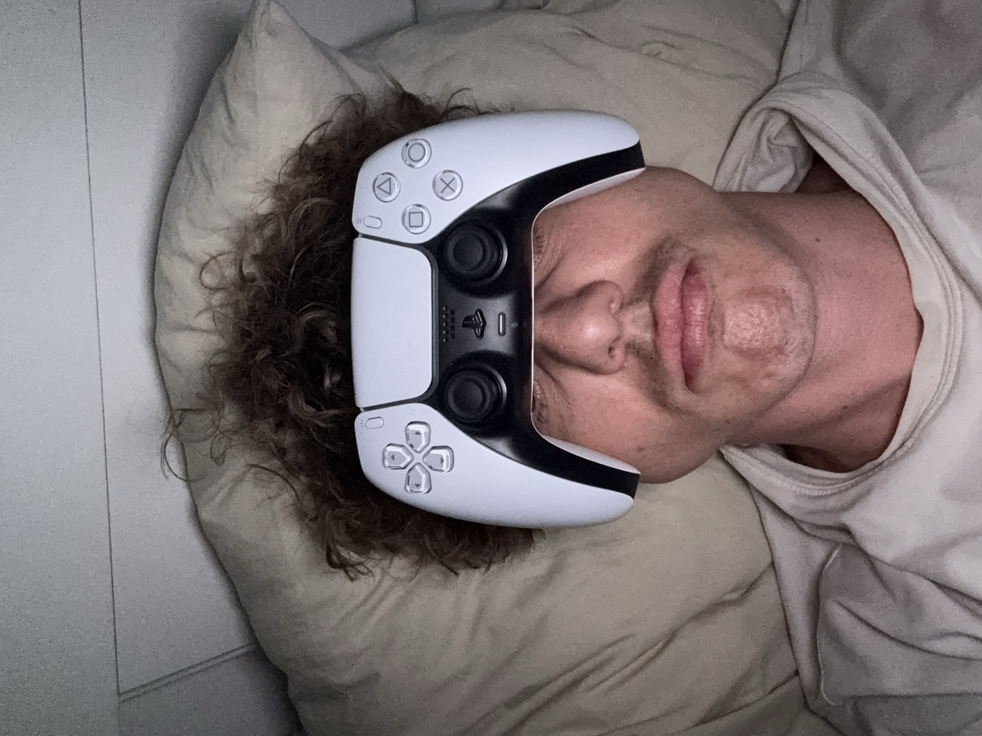 Person plays with PlayStation controller while lying in bed