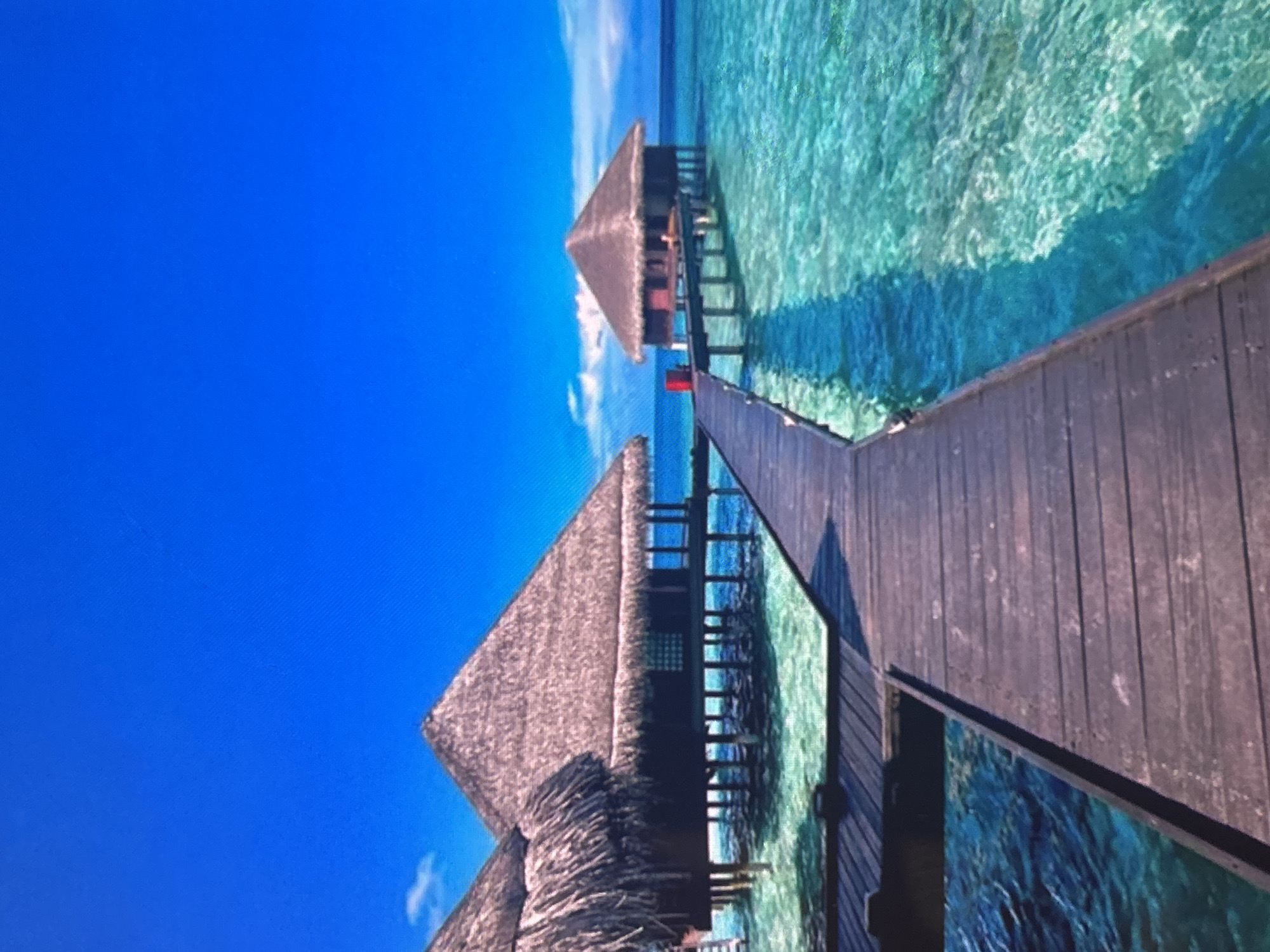Tourist captures rotated photos of tropical overwater bungalow resort