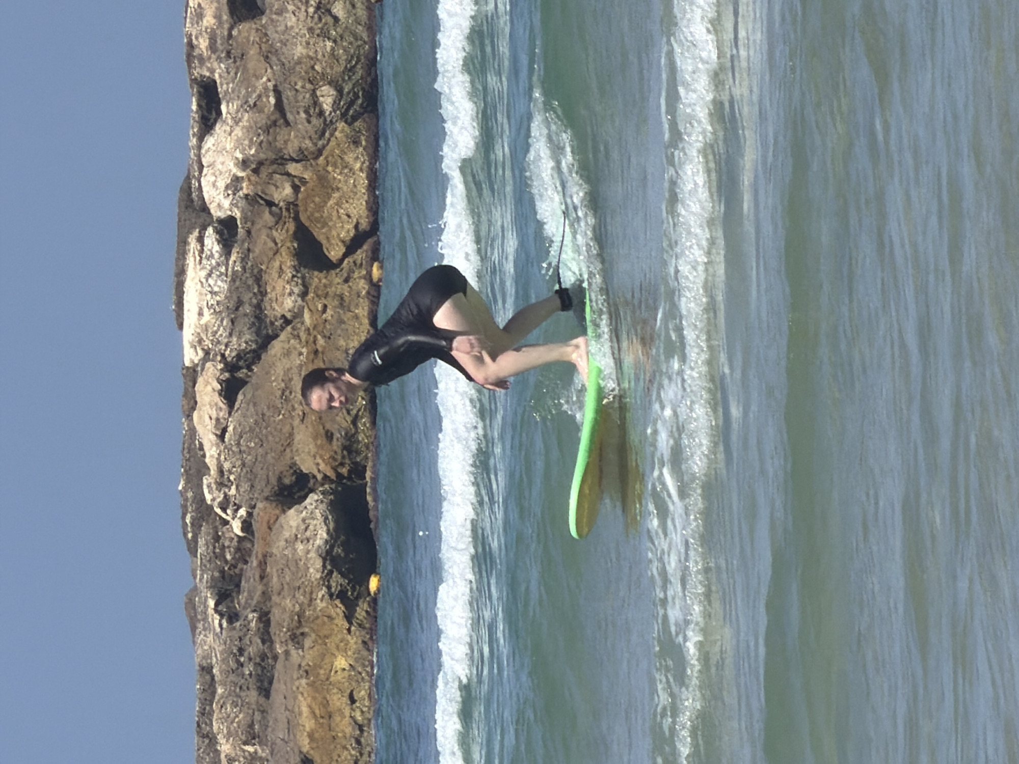 Surfer rides waves near Tel Aviv rocky coastline
