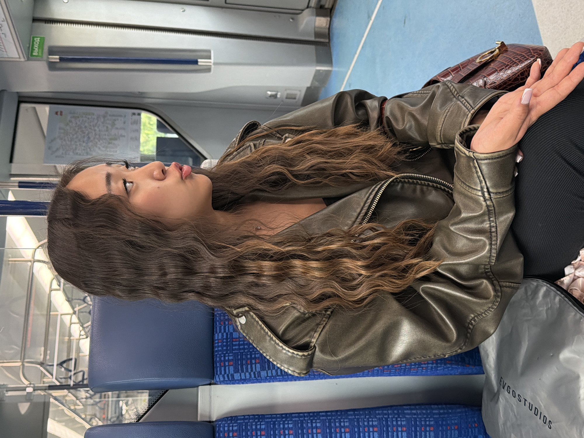 Seated on a Moscow train, metallic jacket, midday ride
