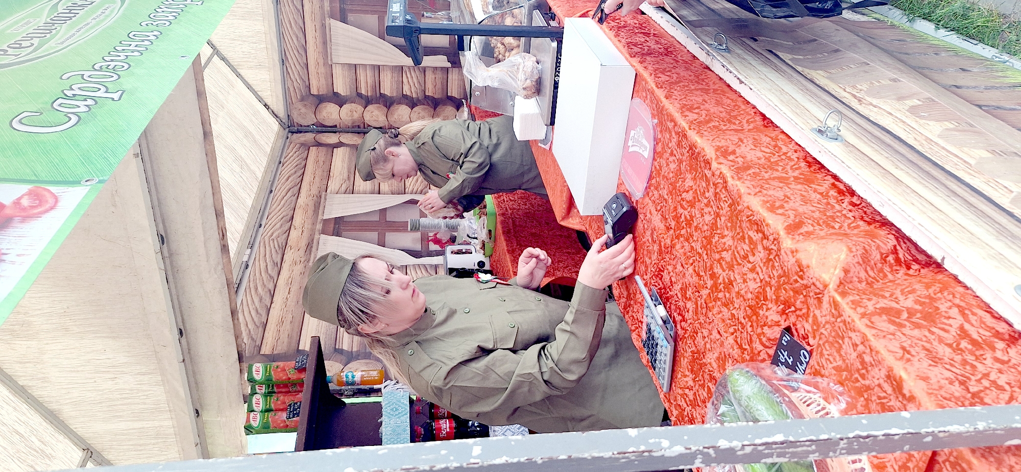Military-uniformed vendors operate market booth in Rechytsa, Belarus