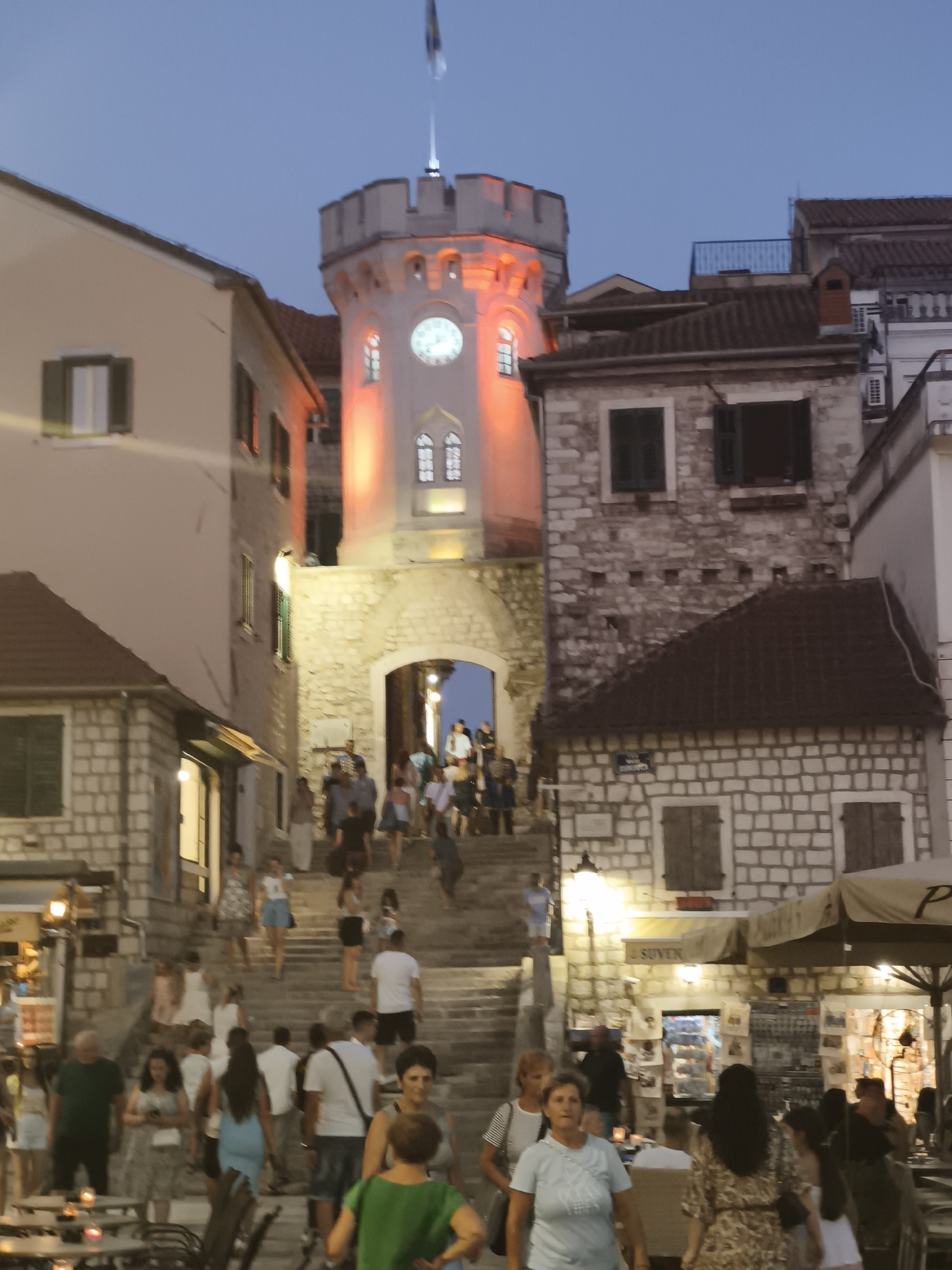Herceg Novi old town at dusk: clock tower, traffic, stone walls