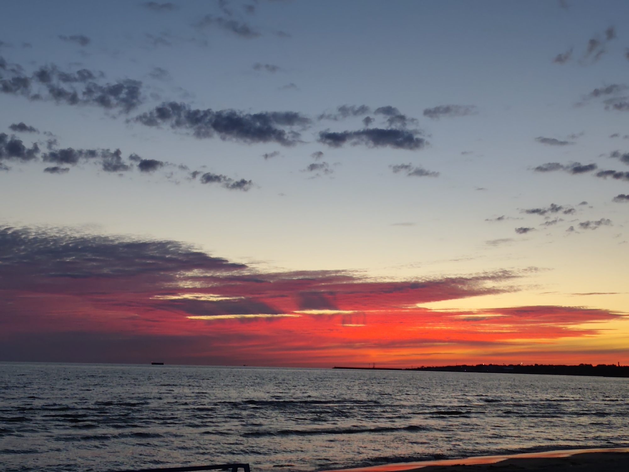 Vivid sunset colors stretch across a calm seascape.