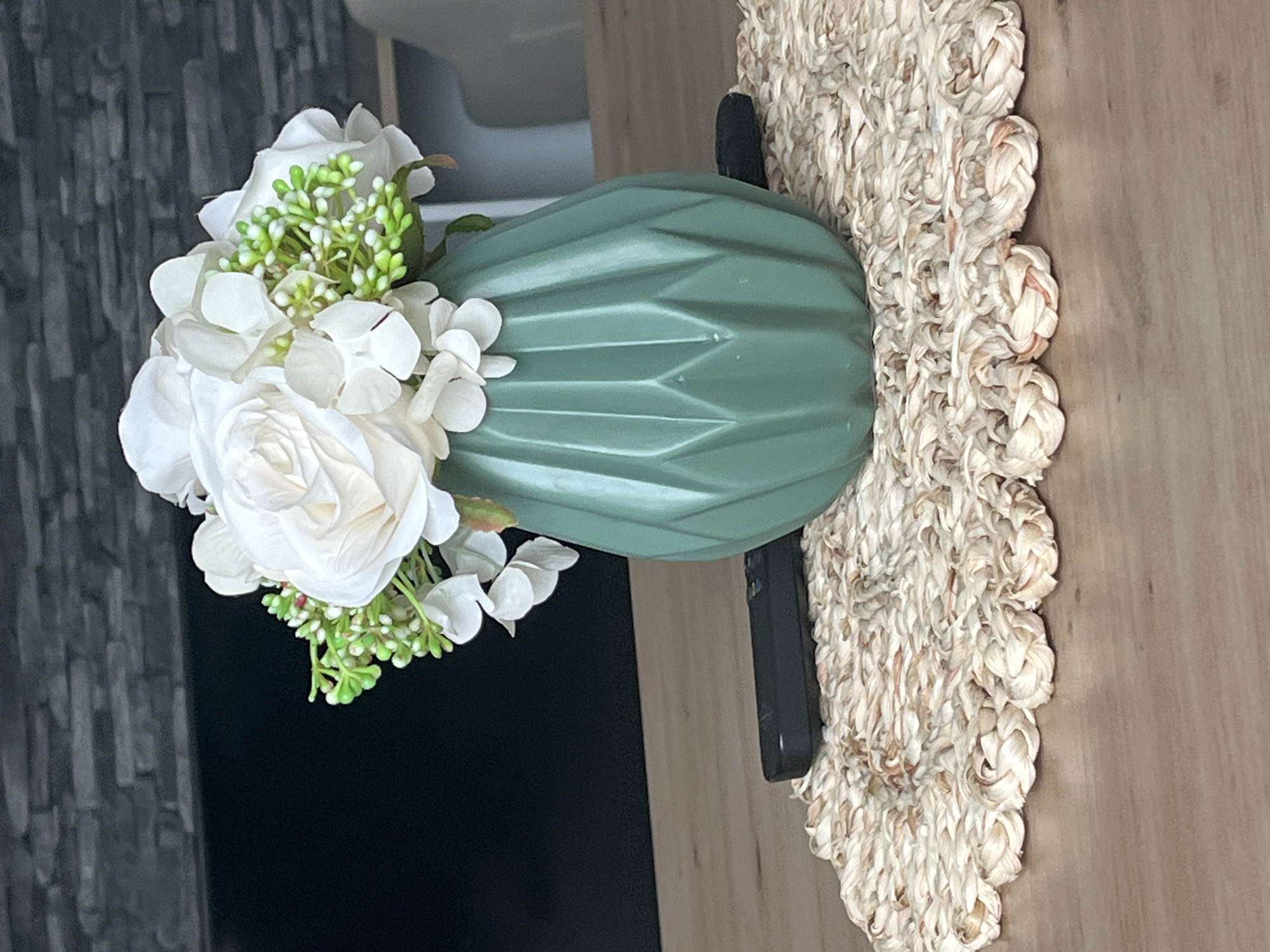 Green geometric vase and white flowers on a wooden table
