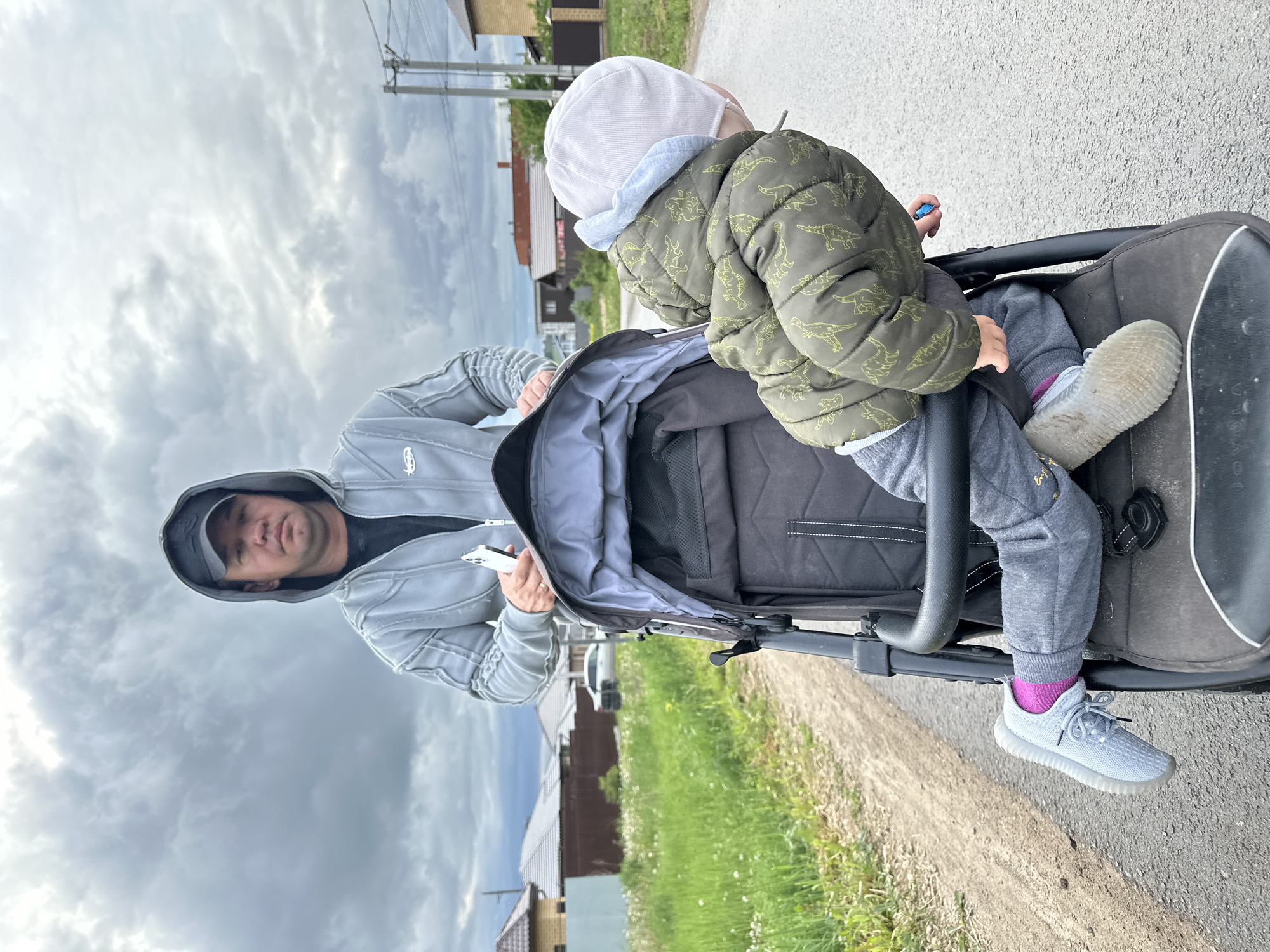 Father pushes stroller through wet streets in Éstachi, Russia