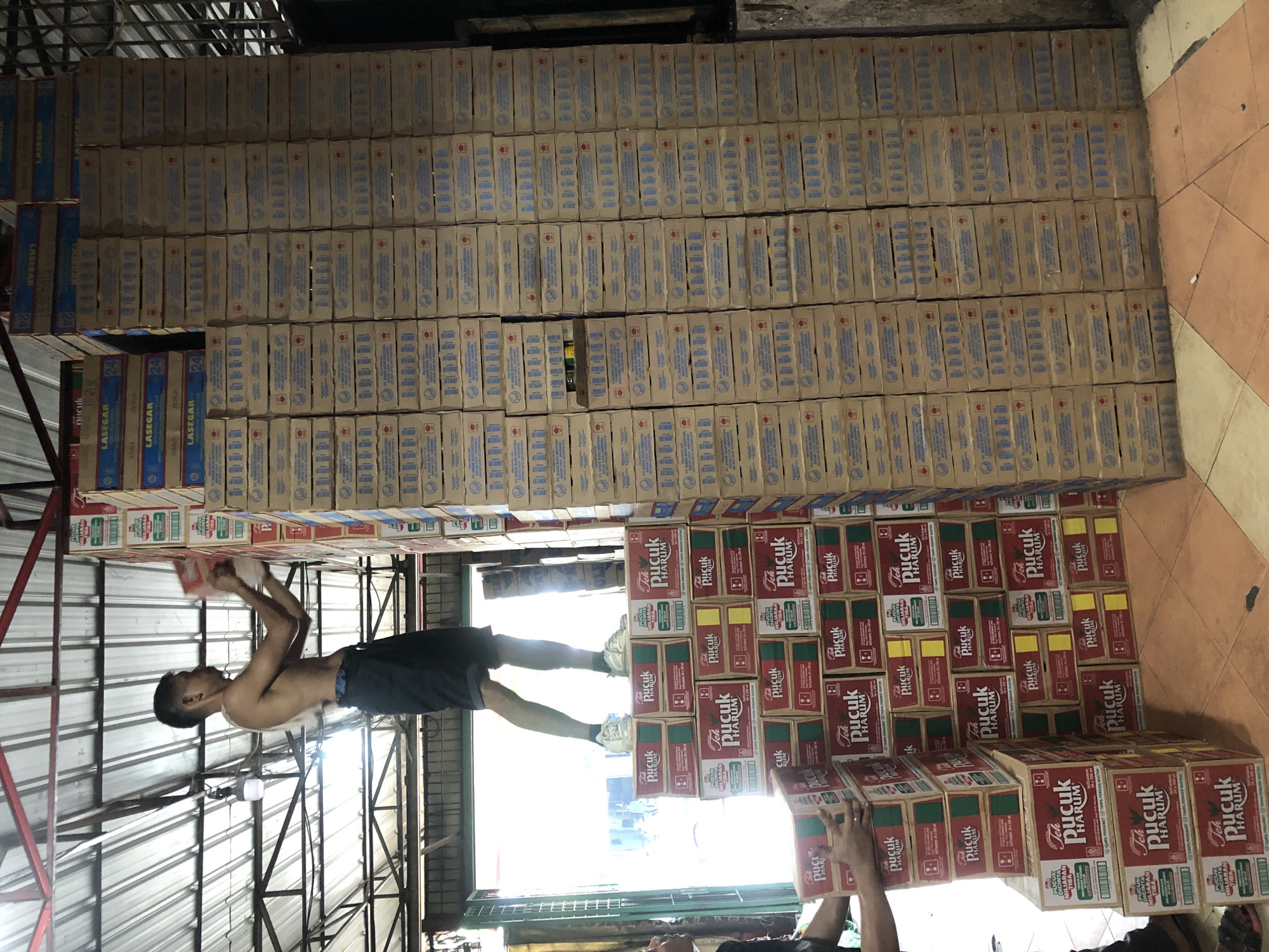 Workers handle beverage inventory in Medan warehouse facility