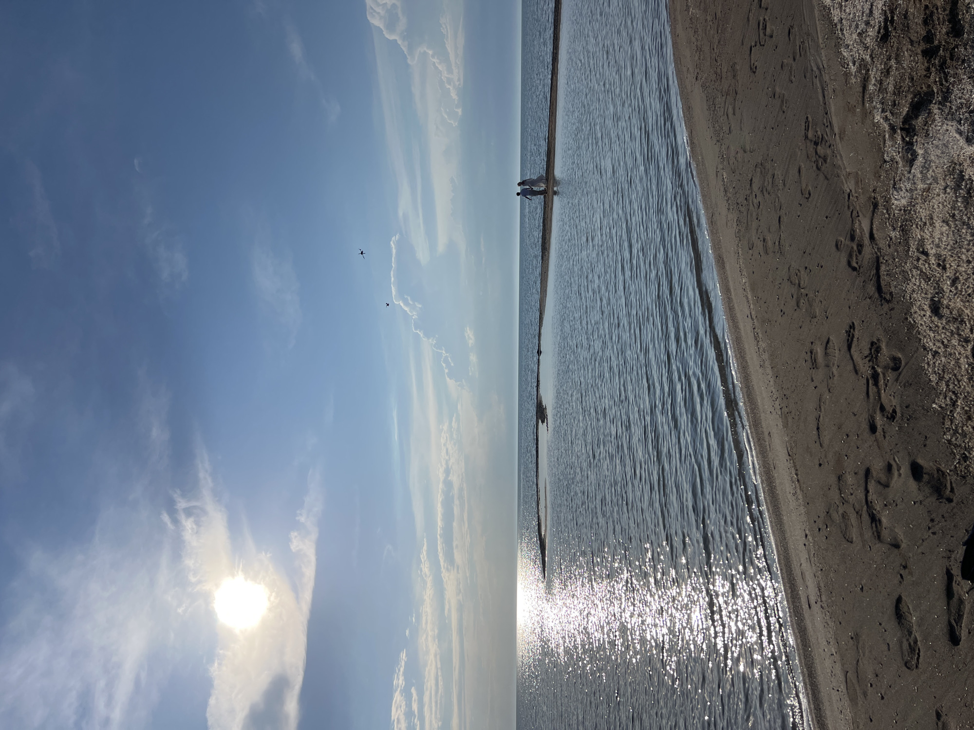 Calm lakeshore beach in Kyrgyzstan, drone resting on dark sand