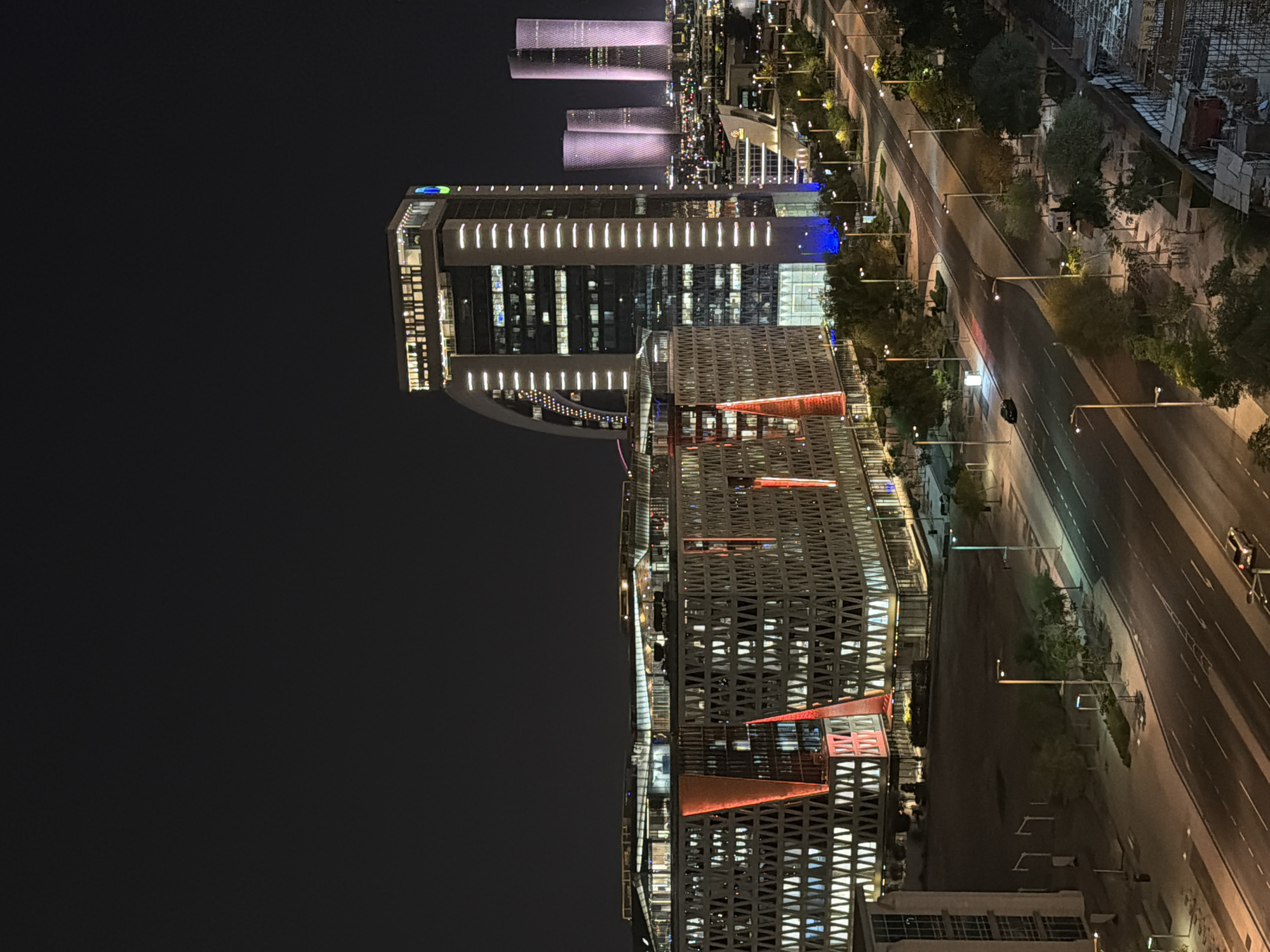 Illuminated waterfront Ferris wheel observed across modern cityscape