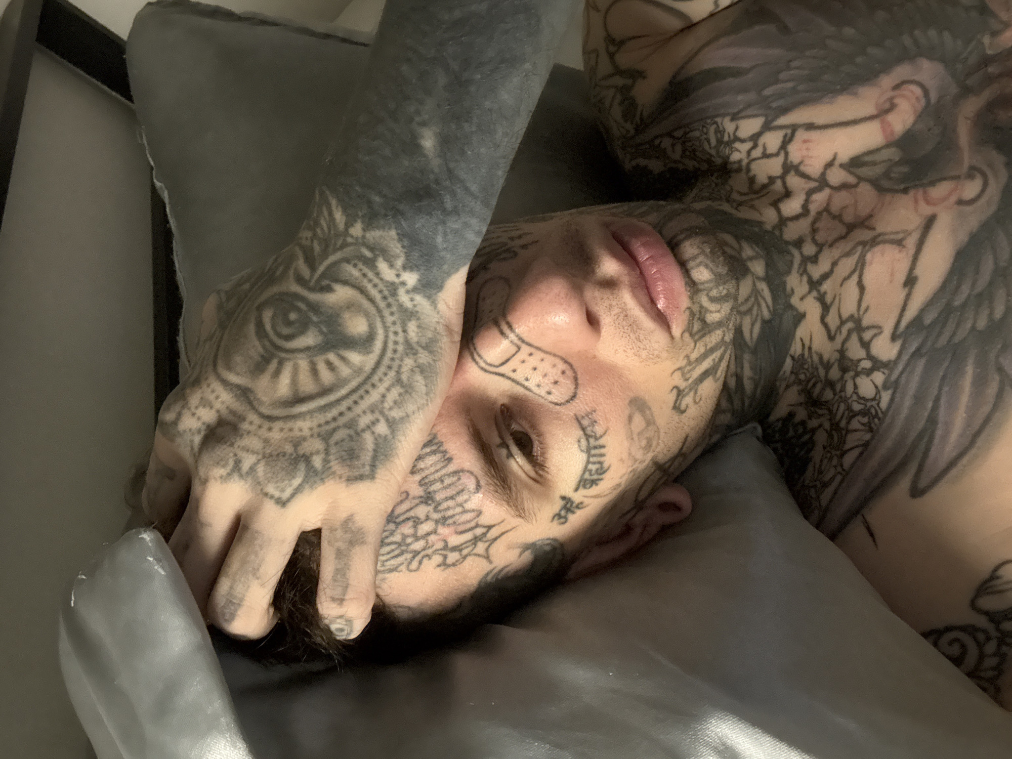 Tattooed person resting on silver pillow in Buenos Aires