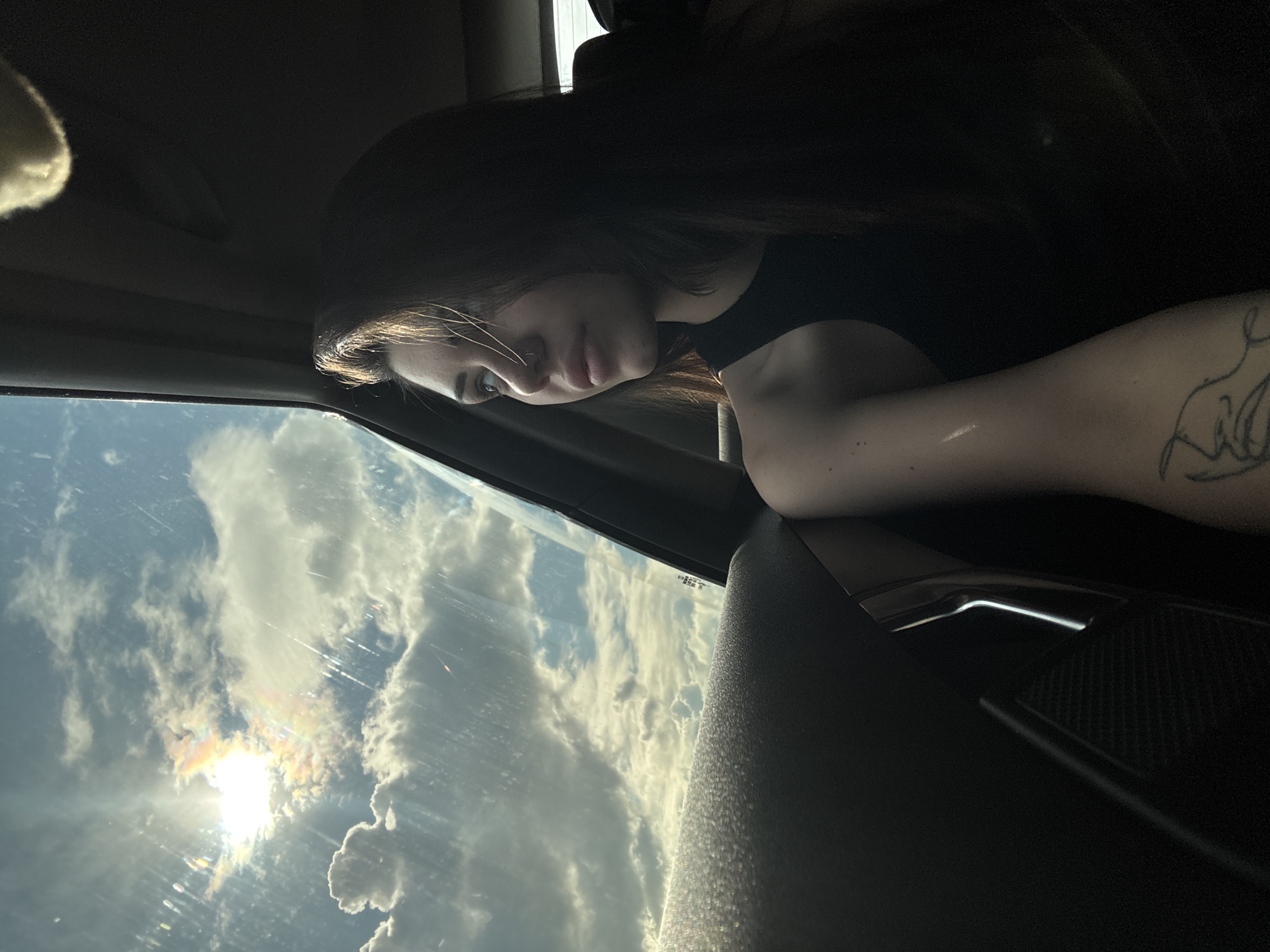 Woman gazes at cloudy sky from car window in Bulgaria