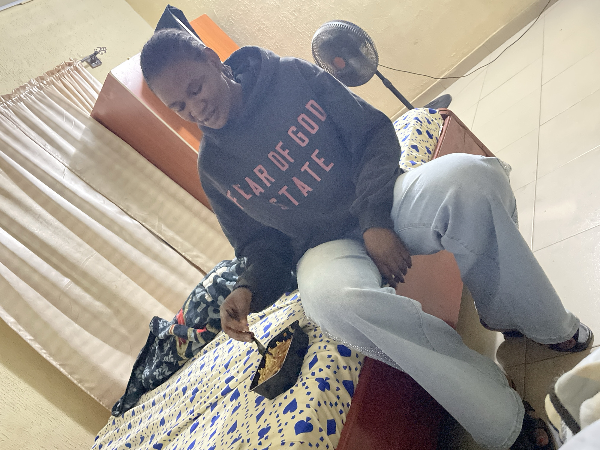 Person eating from container on bed in Jos