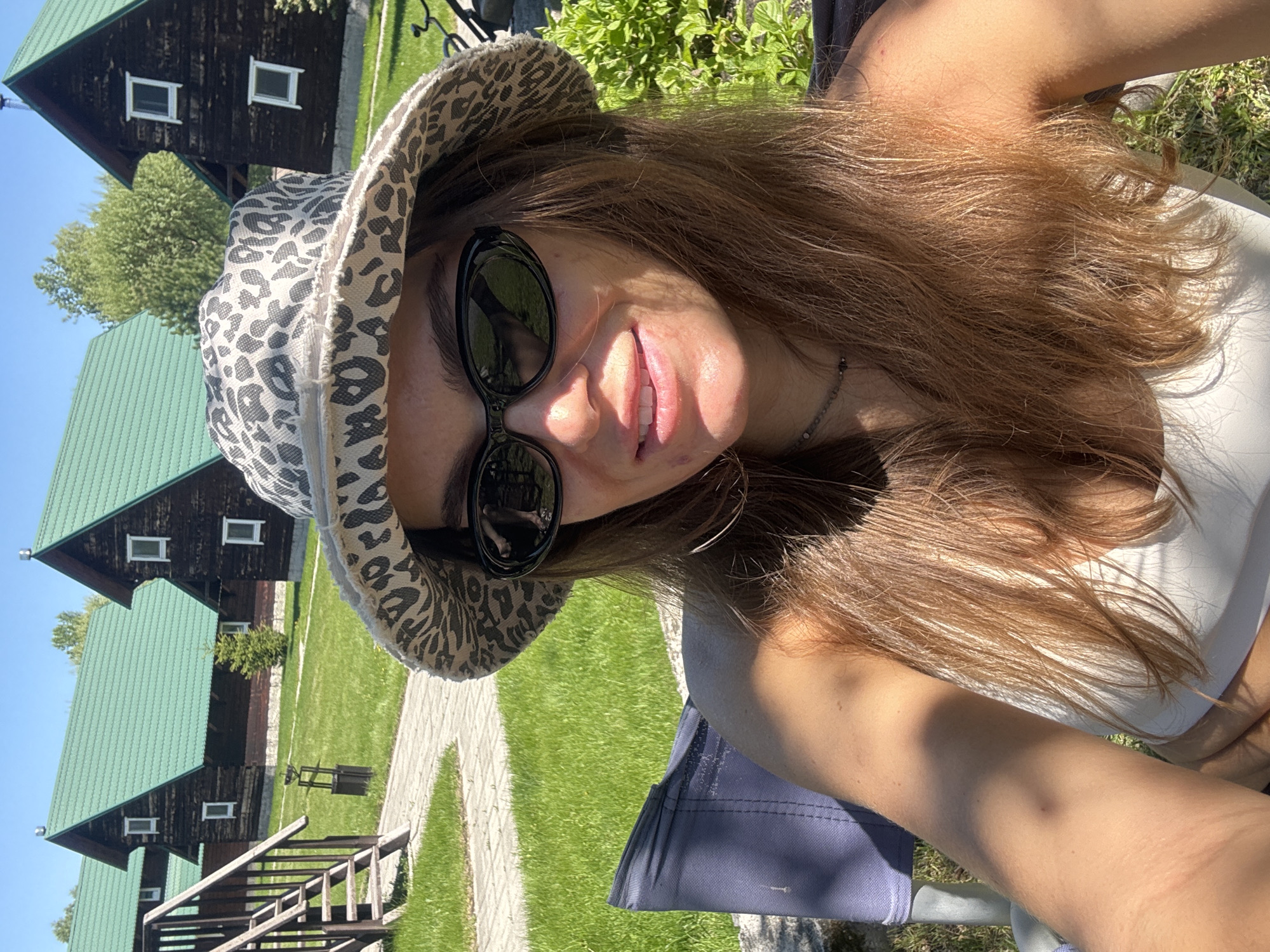 Woman takes selfie near wooden cabins in Aya, Russia