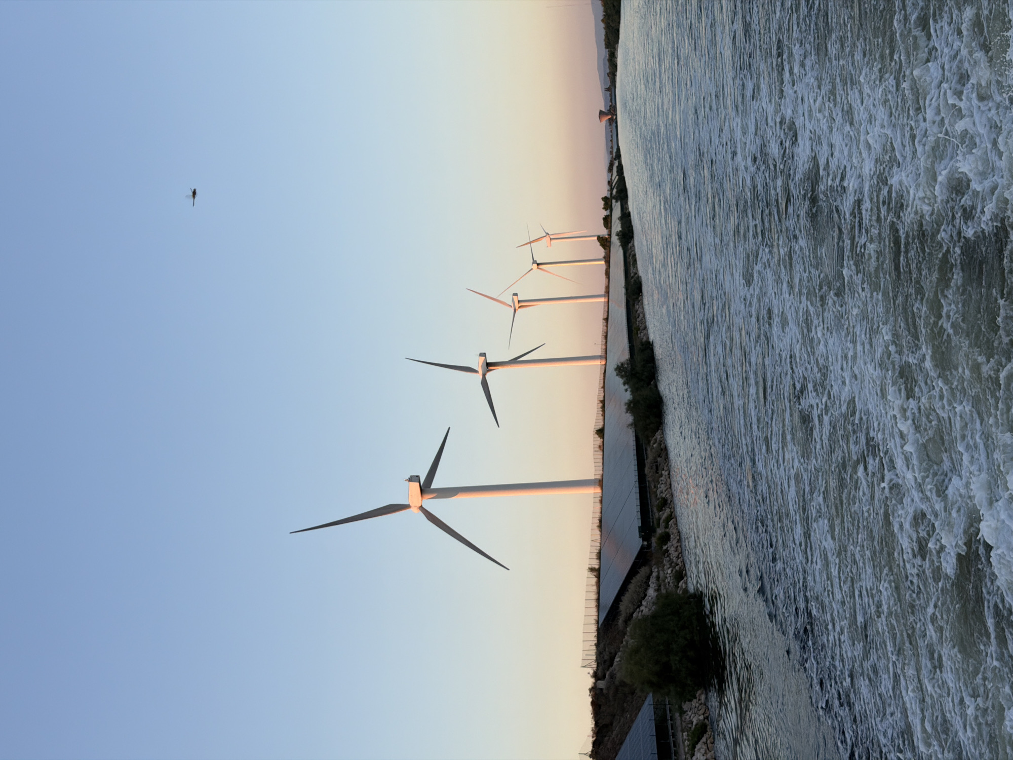Wind turbines and solar panels line a canal in Arles