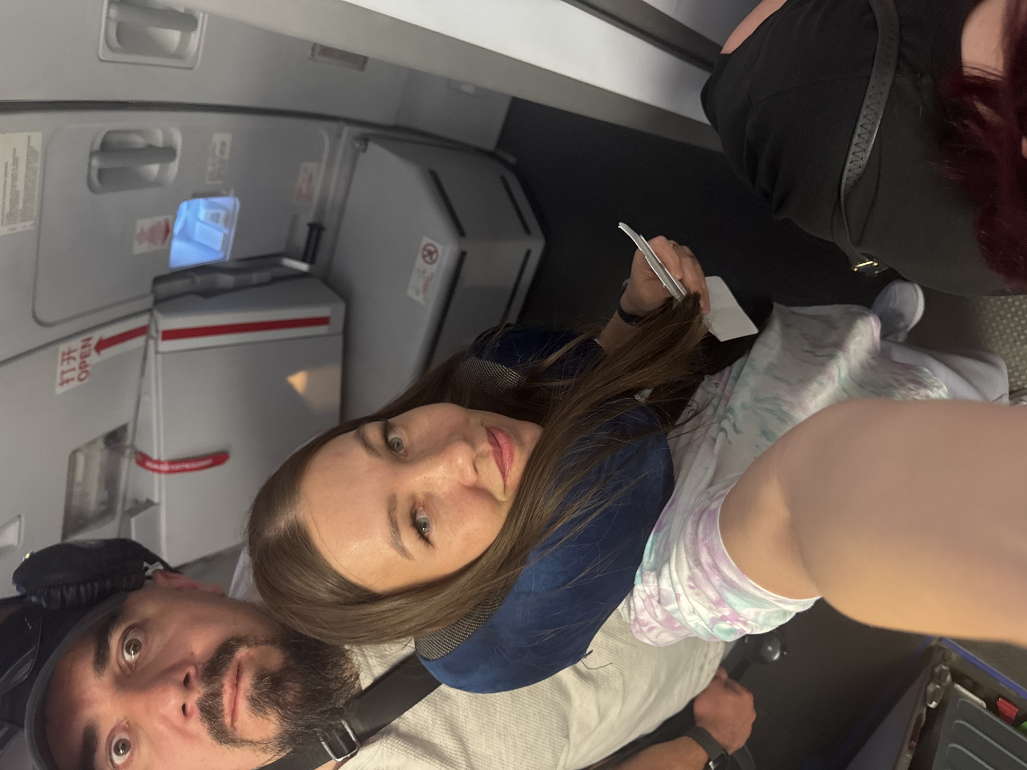 Woman in blue neck pillow photographed on airplane seat